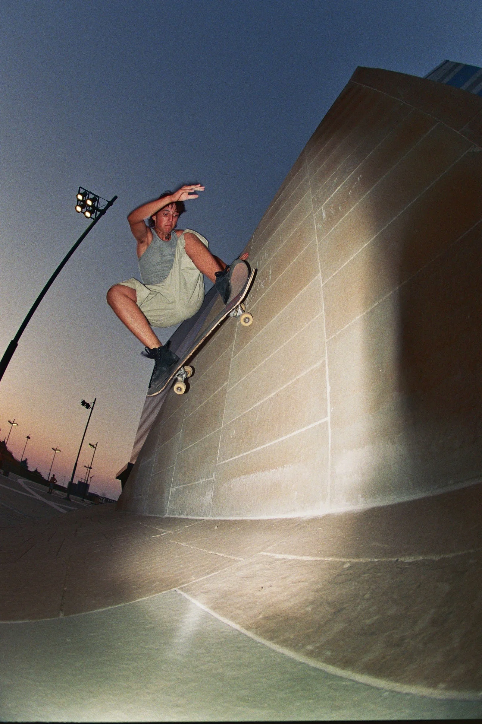 Joven haciendo skate sobre una pared en un parque al atardecer.