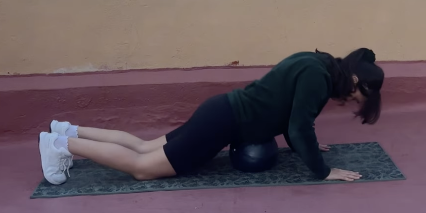 girl laying down on a pilates ball to realease organs