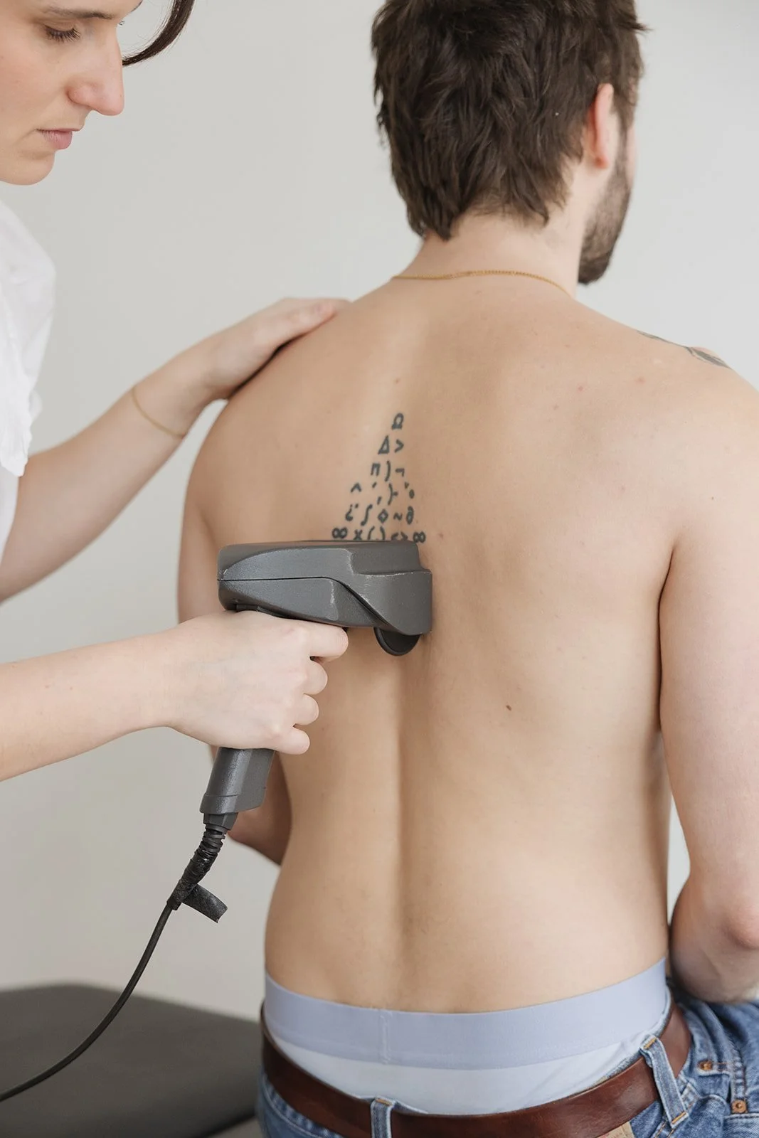 A modern house located on a grassy hillside with a mountain range with snow-covered peaks in the background under a cloudy sky.