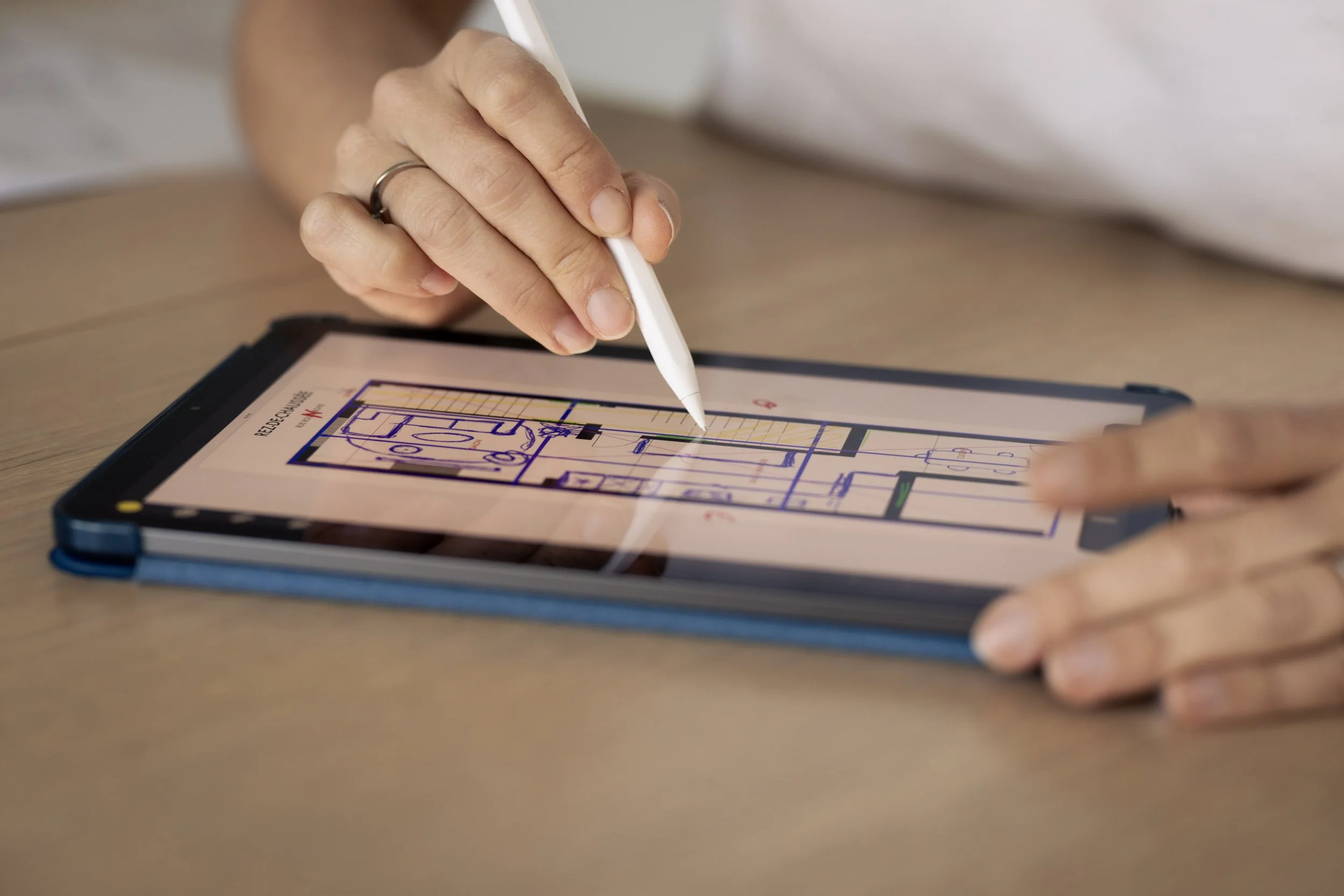Une personne utilisant un stylet pour dessiner un plan architectural sur une tablette numérique.