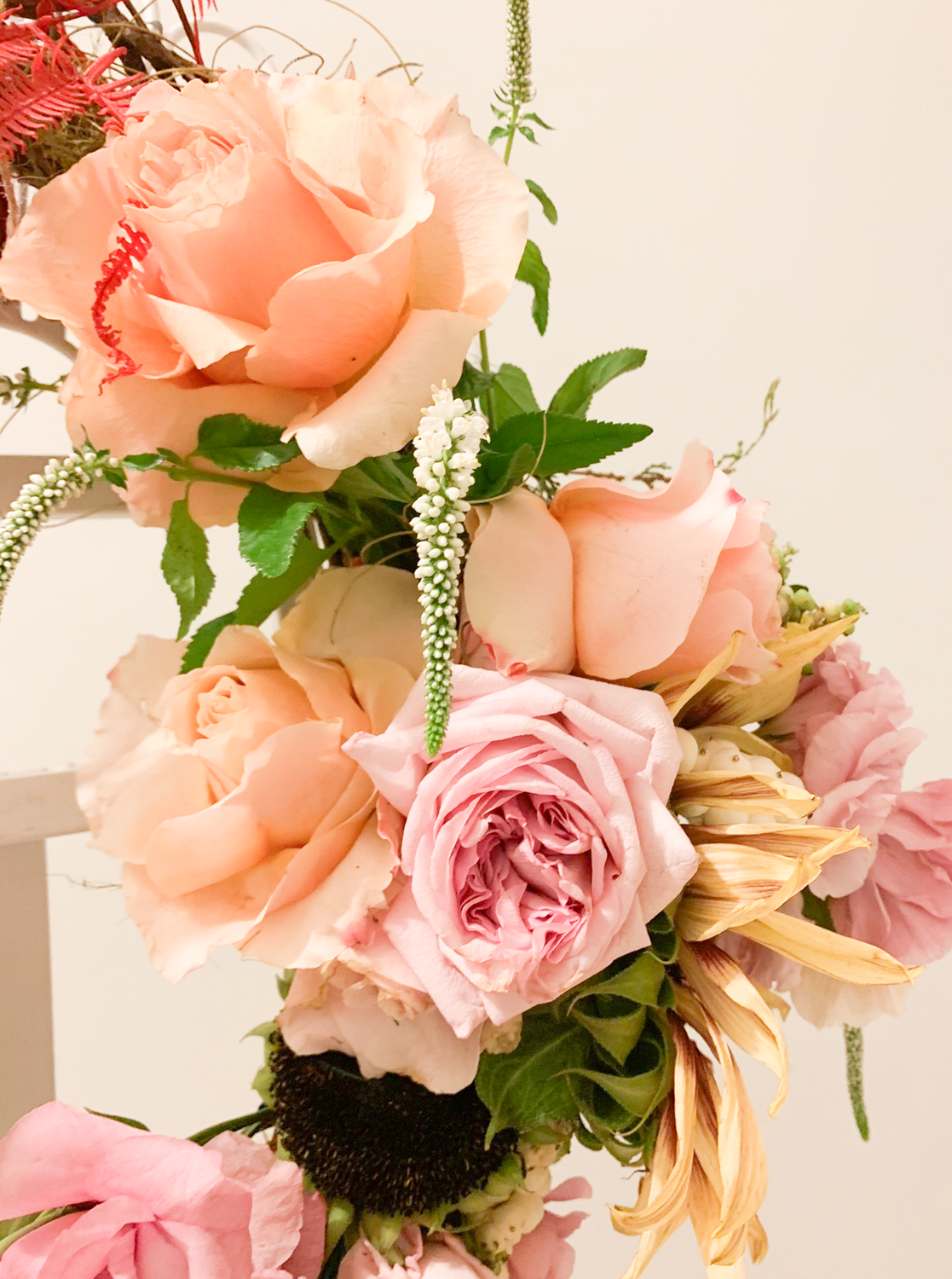 A bouquet of pink and peach roses, with white and green accent flowers and leaves.