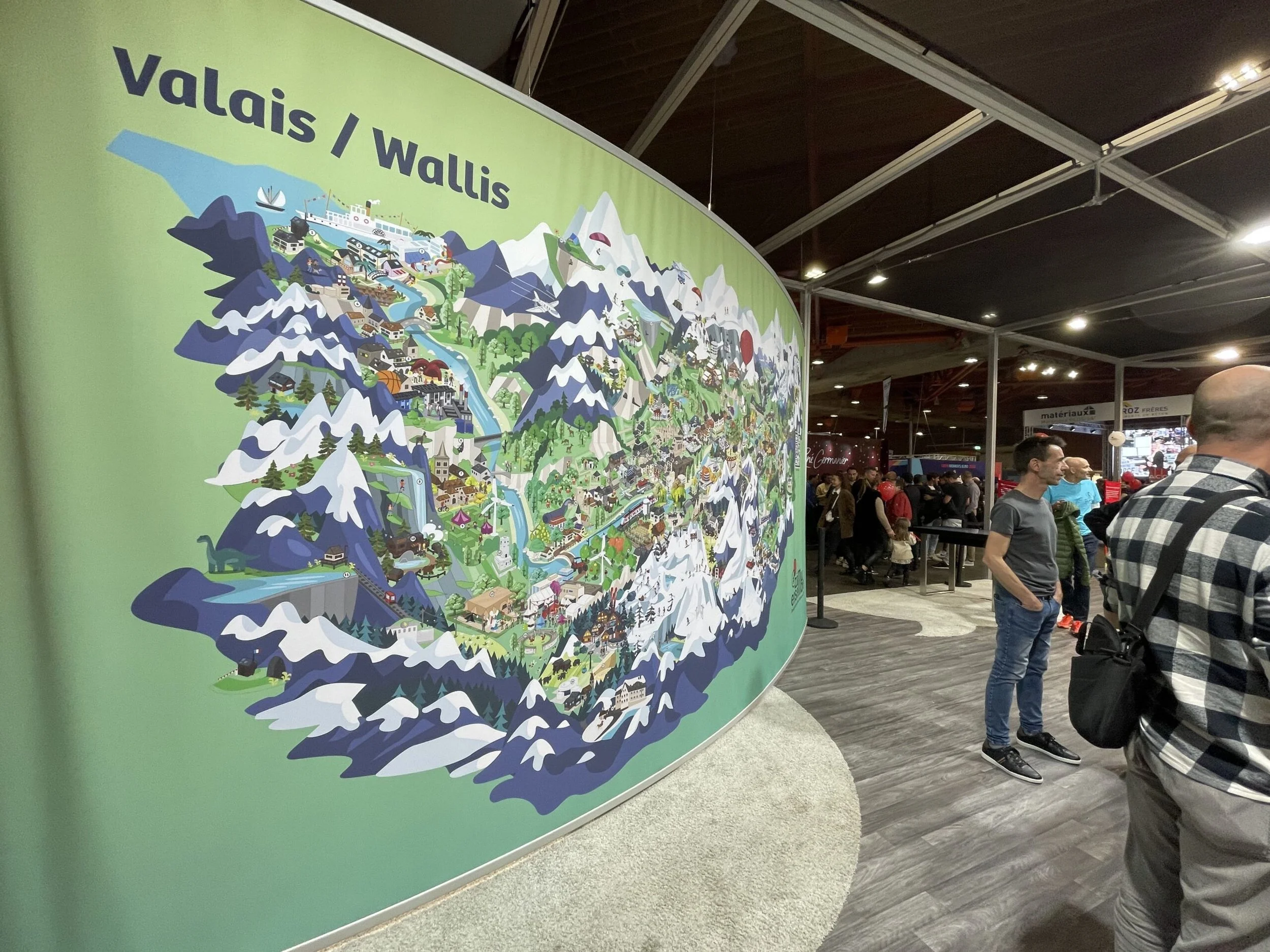 Une photo d'une grande toile sur laquelle est imprimé une illustration d'une carte du Valais dans un style flatdesign. Il y beaucoup de détails et l'image est très colorées.
