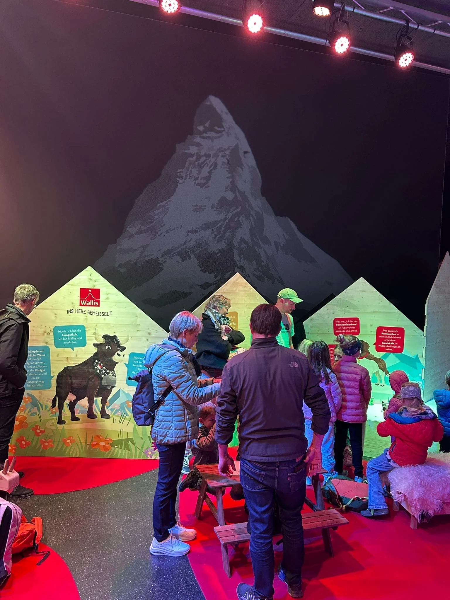 Une photo du stand de Valais/Wallis pour la OLMA. Avec des cabanes en bois illustré avec des dessins pour les enfants.