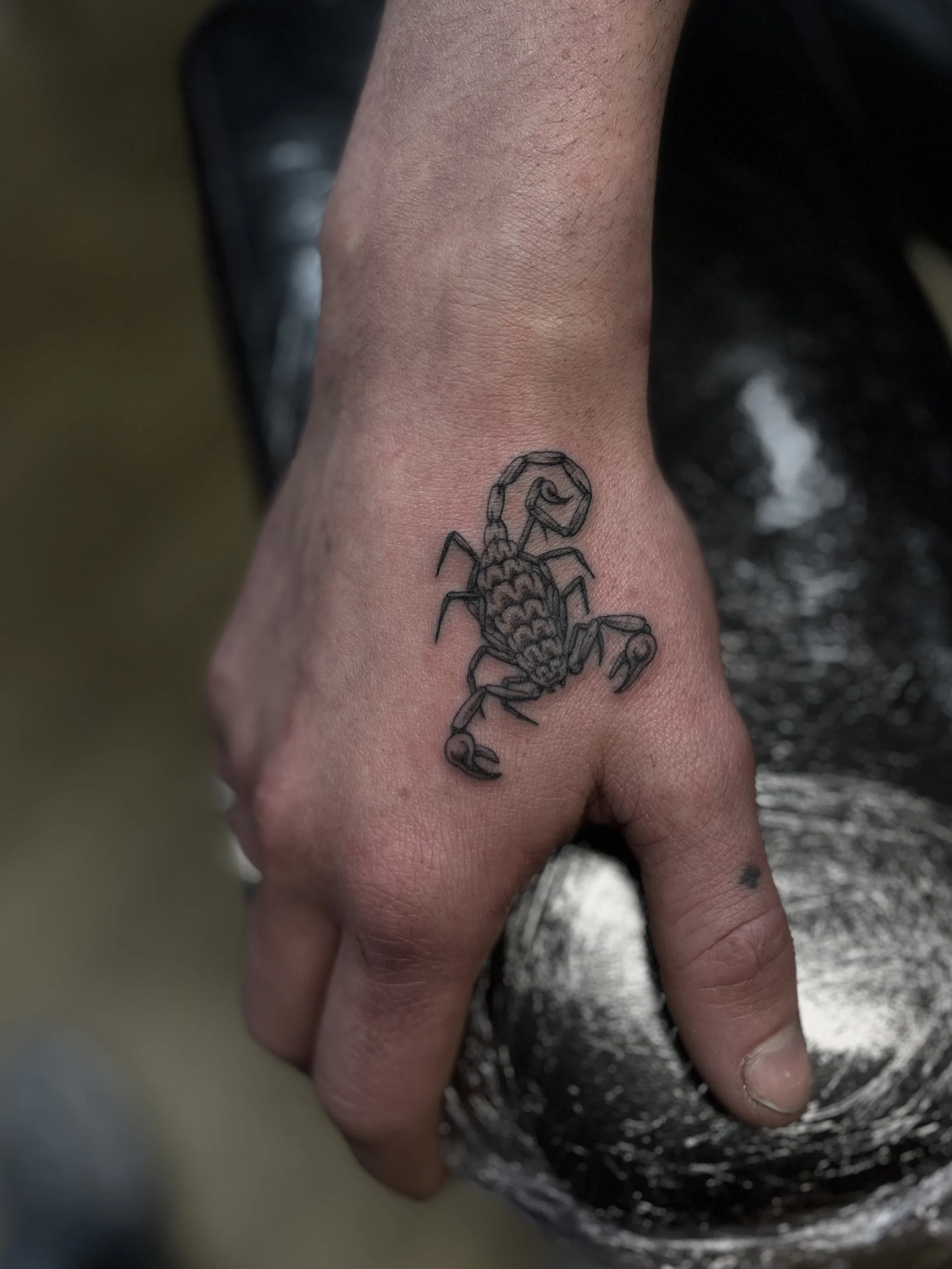 Single needle black and grey scorpion tattoo on the hand, done at Frith Street Tattoos, Soho, central London.