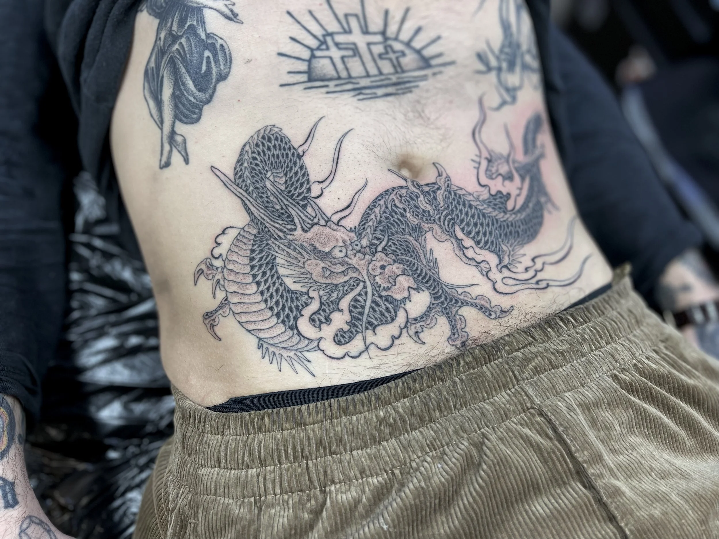 Fine line, single needle dragon tattoo on the lower belly, done at Frith Street Tattoos, soho, central London.