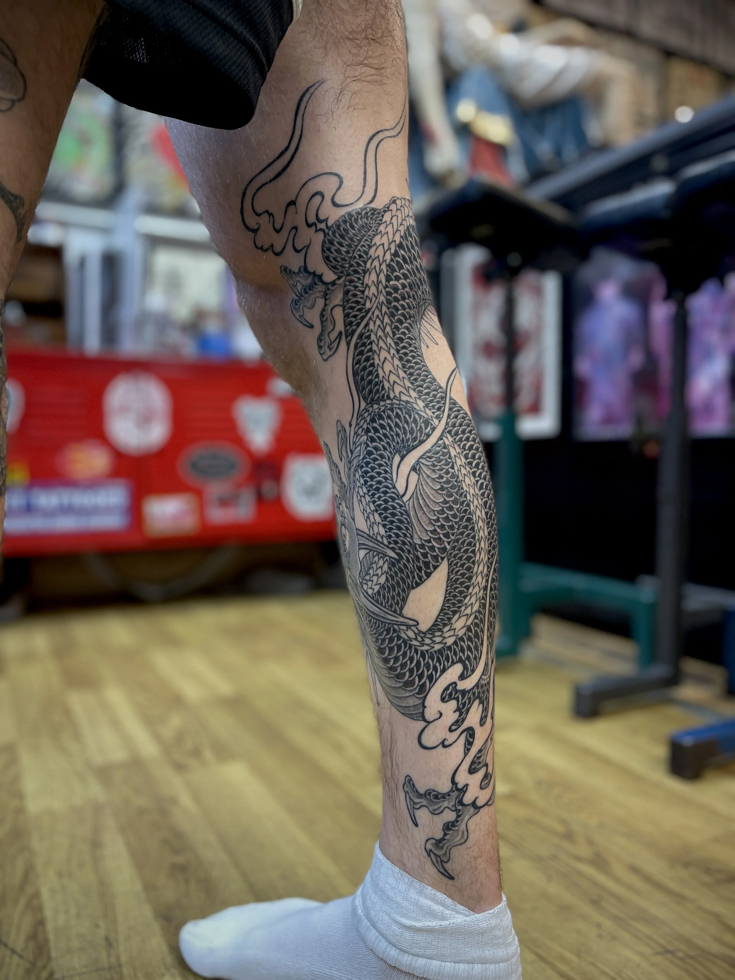 Black and grey Japanese tattoo of a dragon on the leg, tattooed in Soho, central London.
