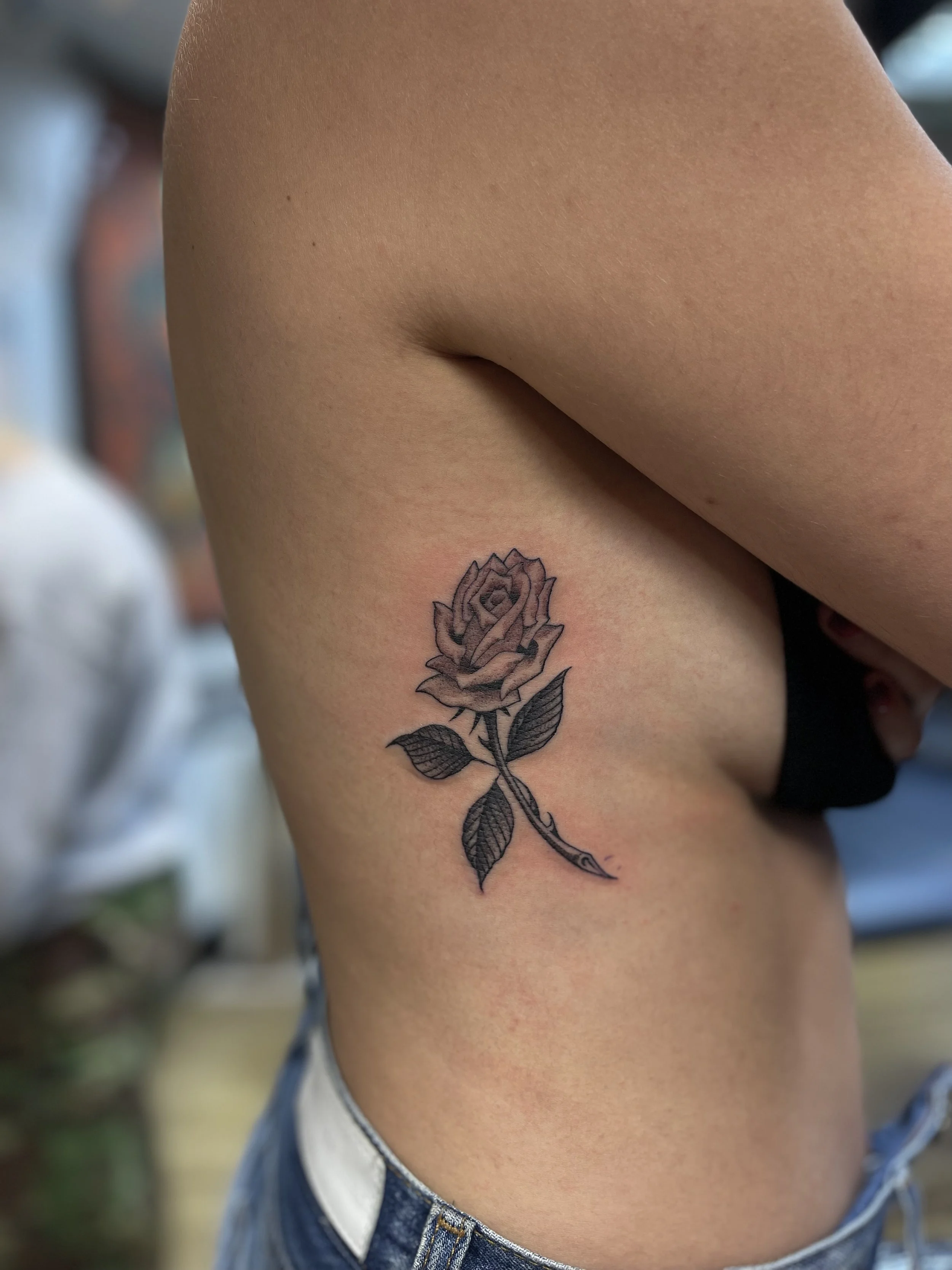 Single needle fine line rose tattoo on the ribs, done at Frith Street Tattoos, Soho, central London.