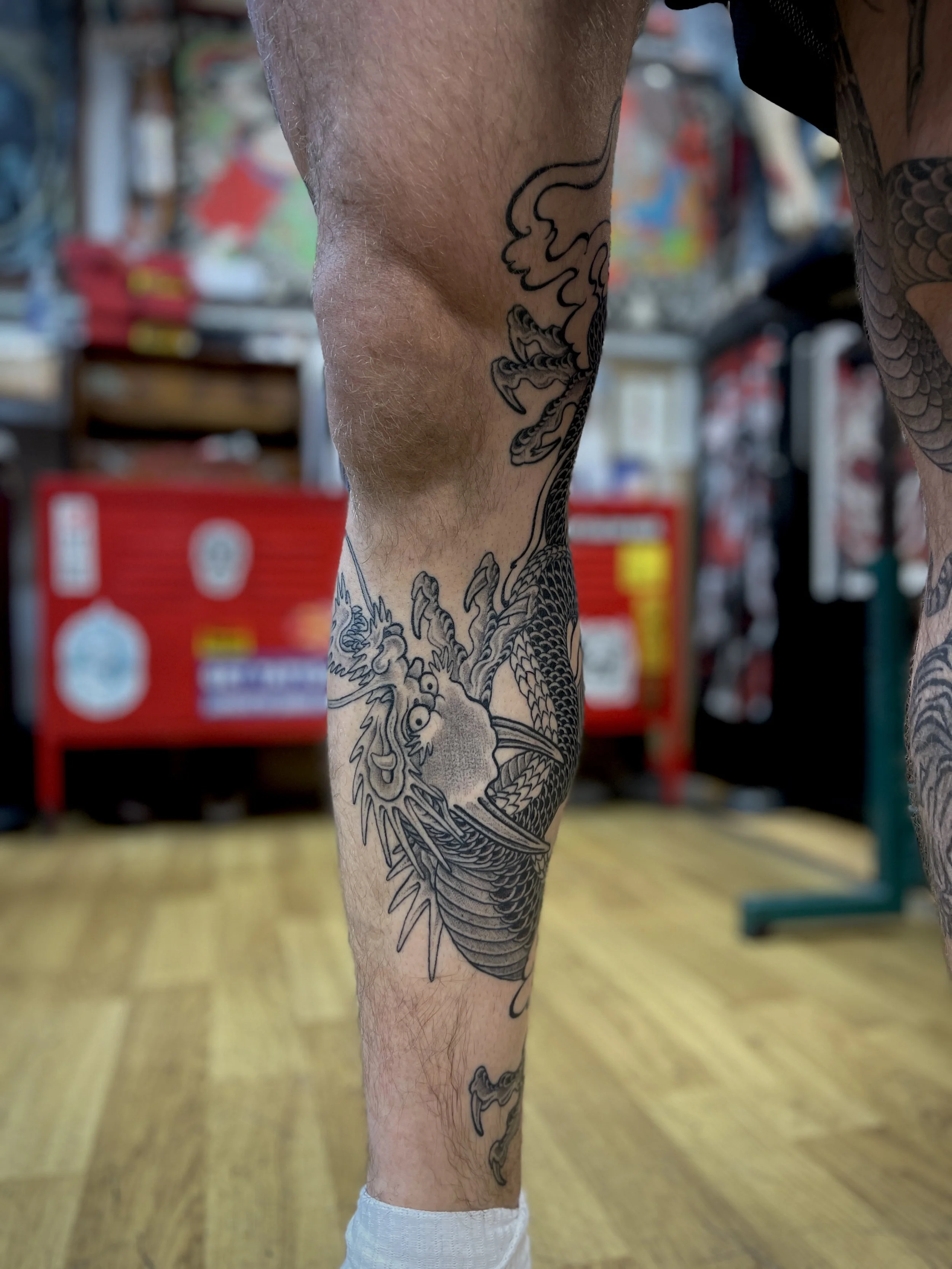 Black and grey Japanese tattoo of a dragon on the leg, tattooed in central London.