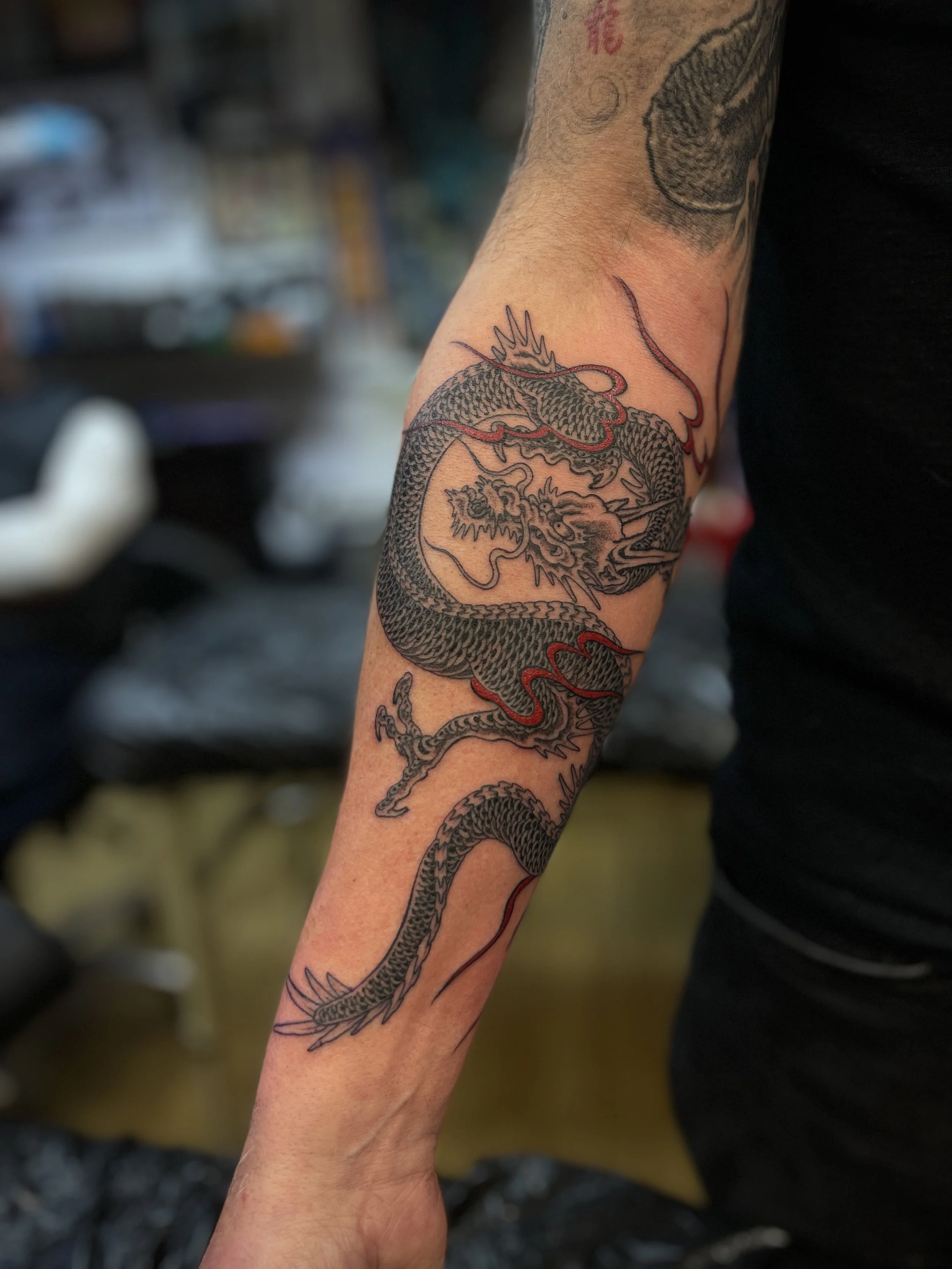 Fine line black and grey dragon tattoo on the forearm, done at Frith Street Tattoos, Soho, central London.