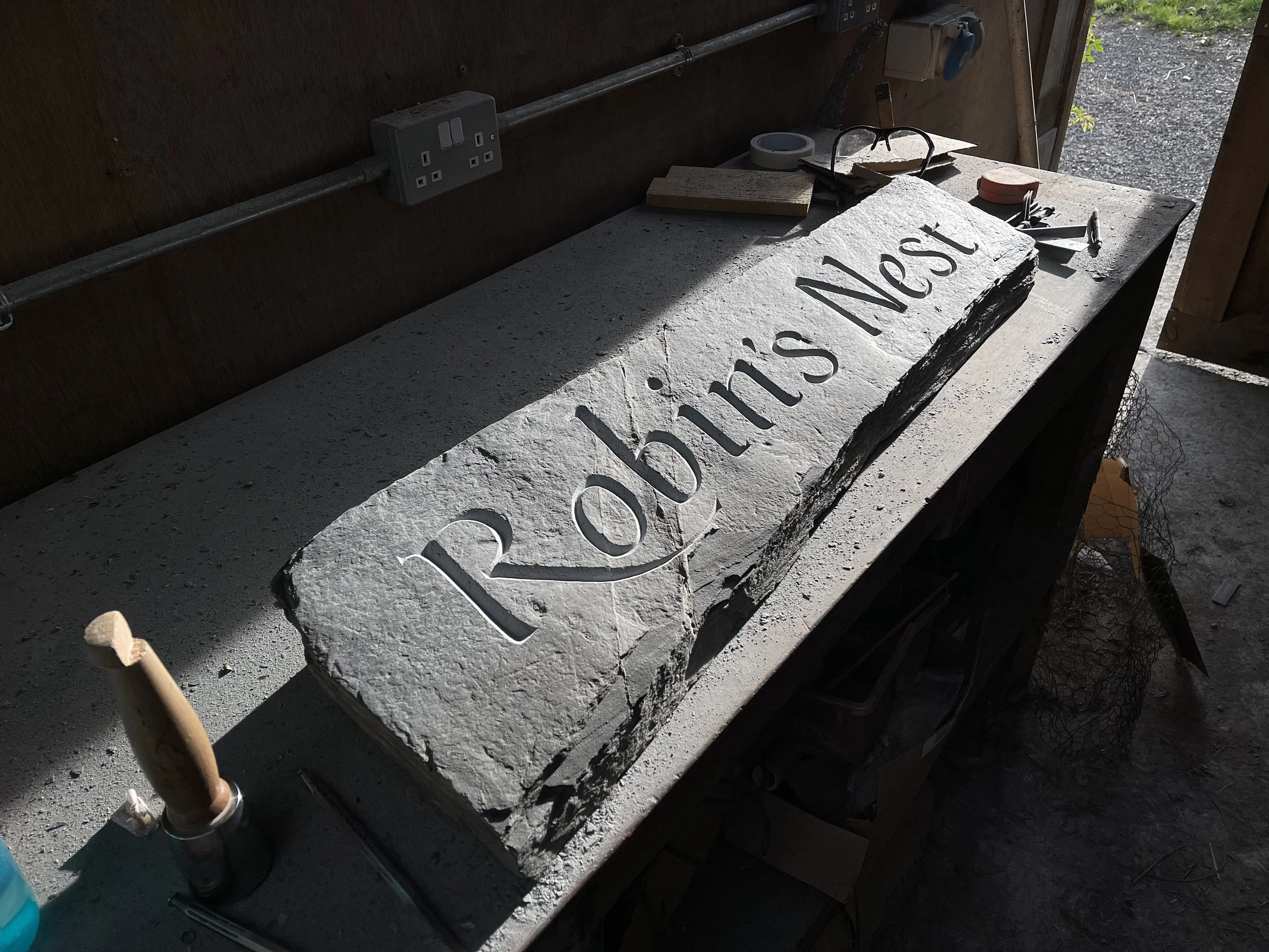 Stone carved house-sign in riven Delabole slate.