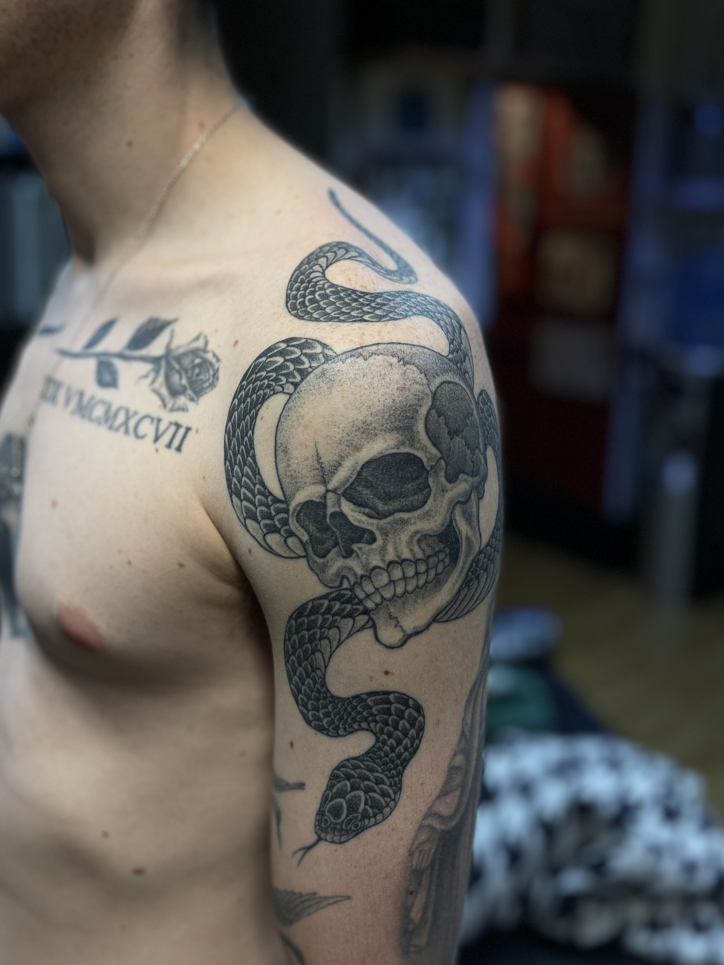 Fine line black and grey tattoo of a skull and snake, done at Frith Street Tattoos, Soho, central London.