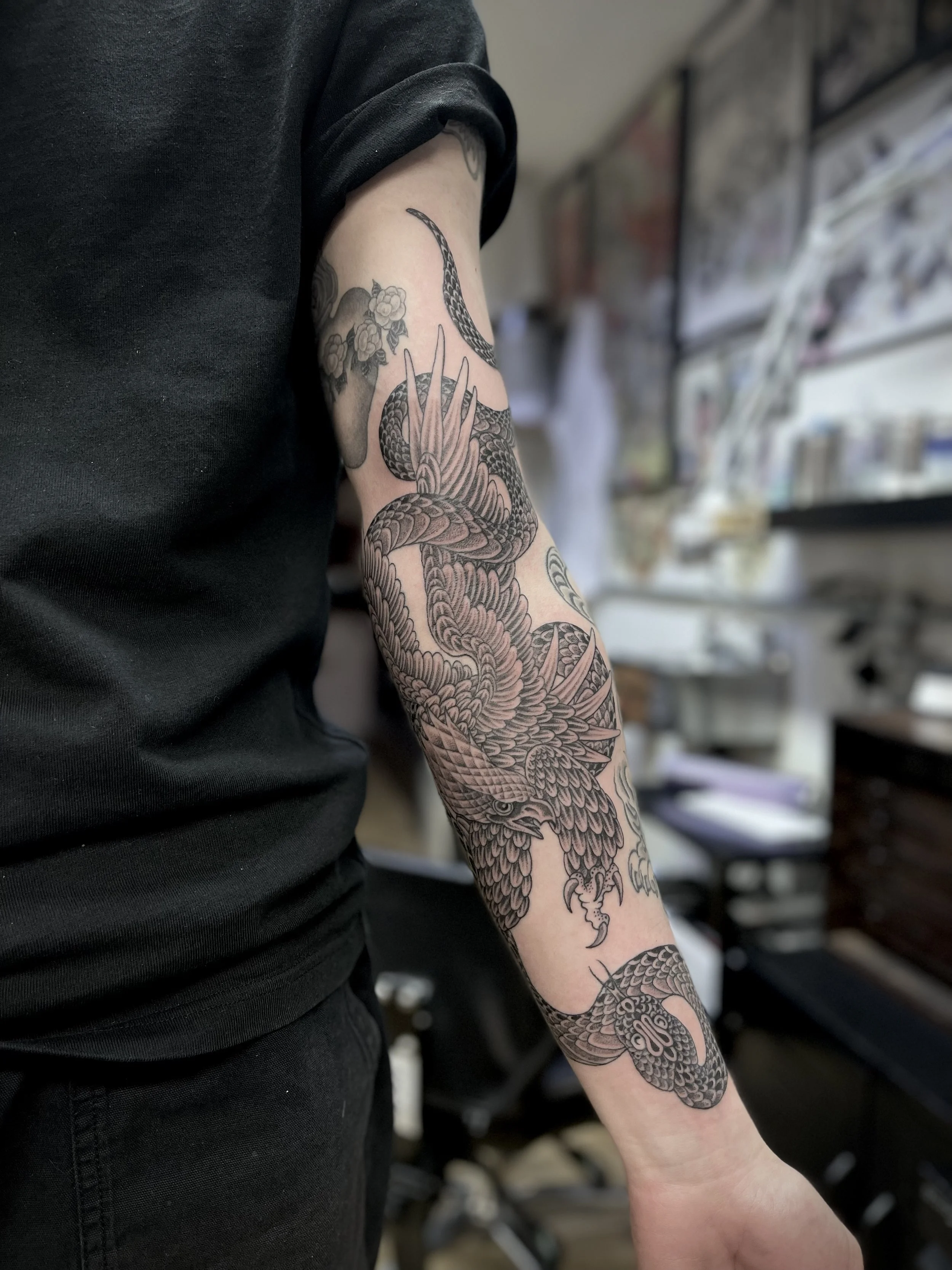 Fine line, black and grey eagle and snake tattoo on the arm, done at Frith Street Tattoos, Soho, central London.