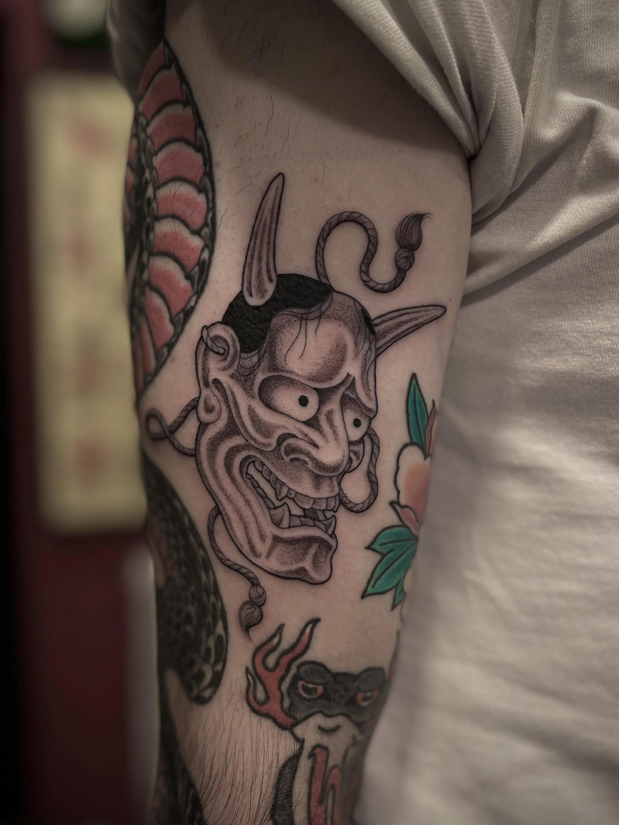 Fine line black and grey hannya tattoo on the upper arm, done at Frith Street Tattoos, Soho, central London.