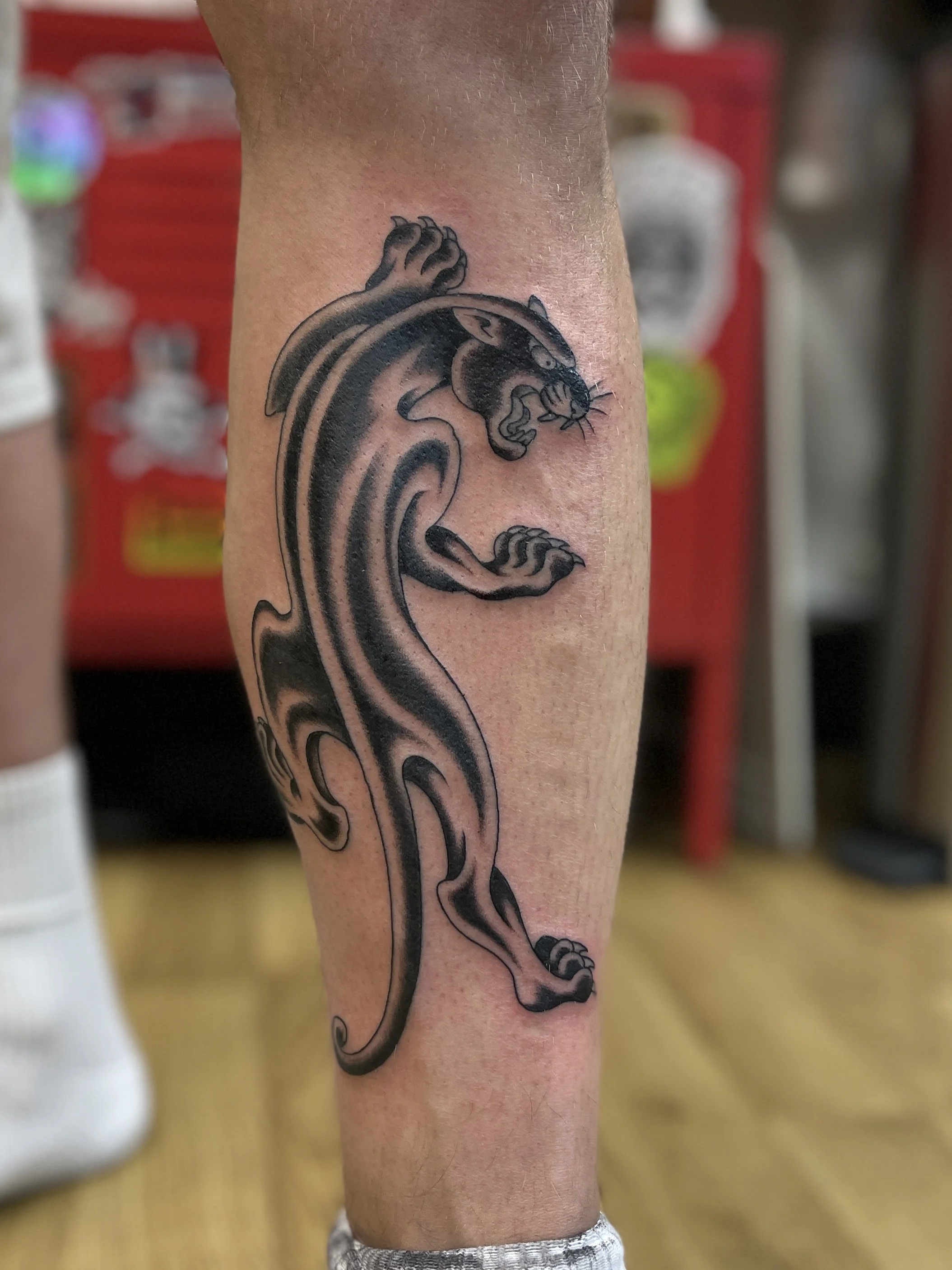 Fine line traditional panther tattoo on the leg, done at Frith Street Tattoos.
