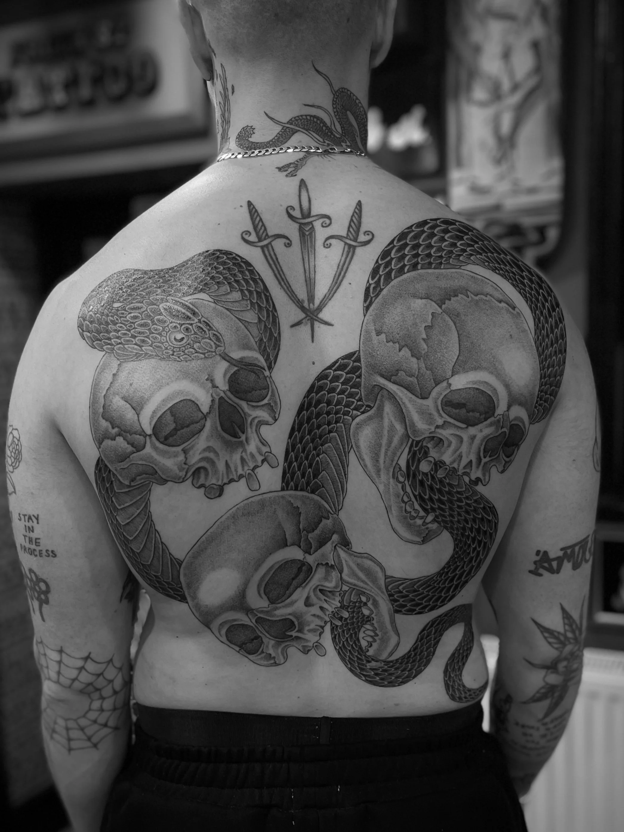 Black and grey back piece of skulls and a snake, tattooed at Frith Street Tattoos, Soho, central London.