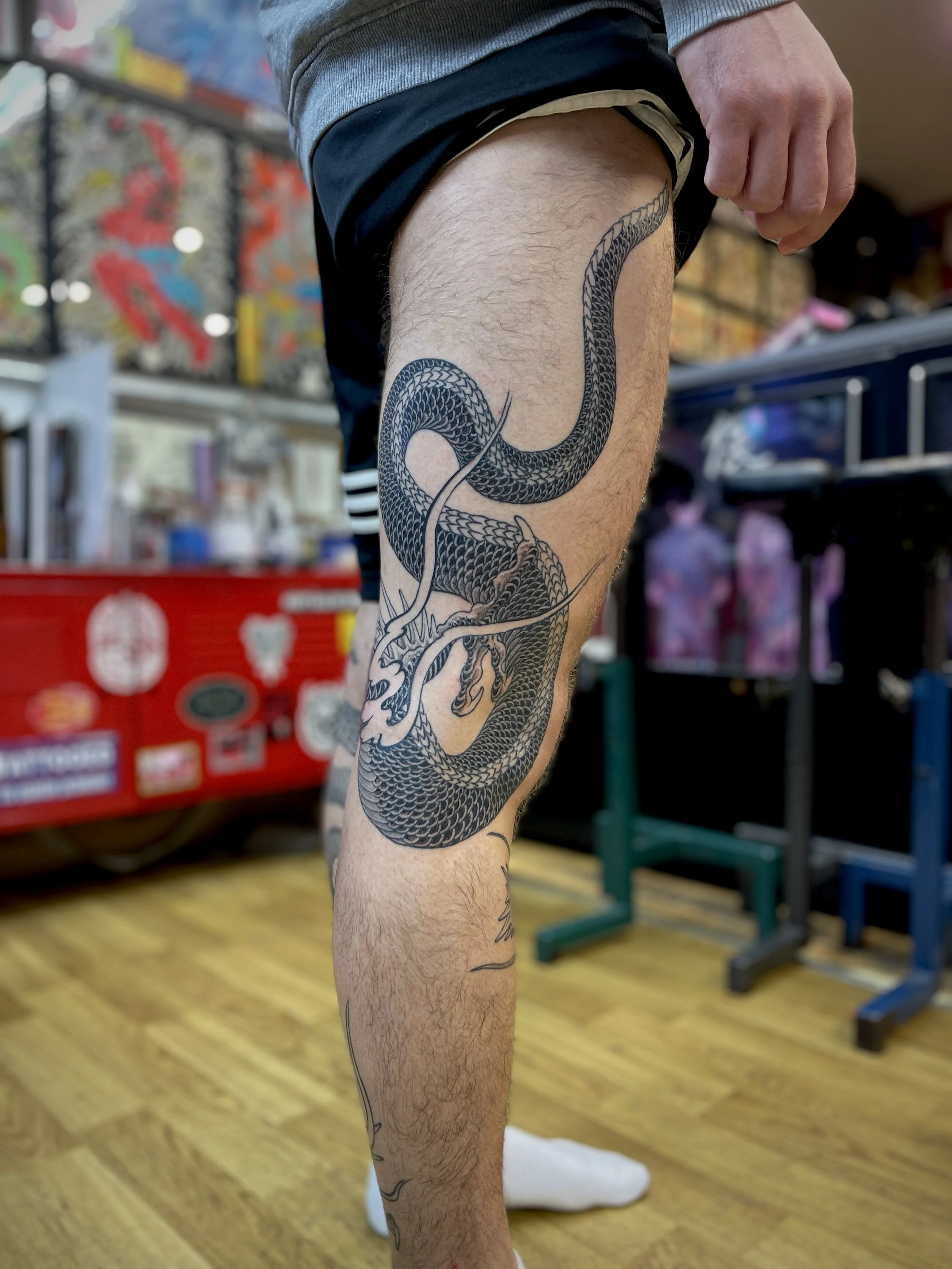 Black and grey Japanese tattoo of a dragon on the leg. Made in London.