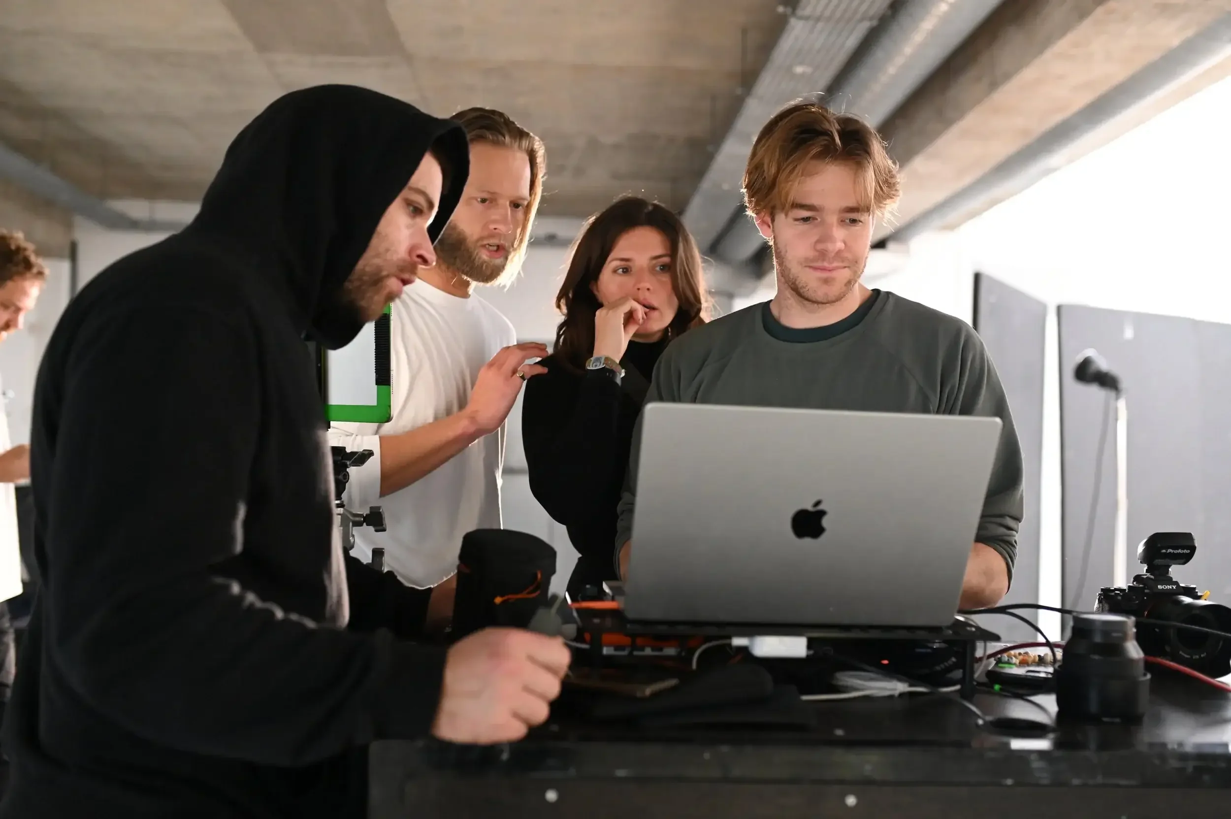 Group of five professionals from shootshare working together with a laptop and camera on a table in a studio setting.