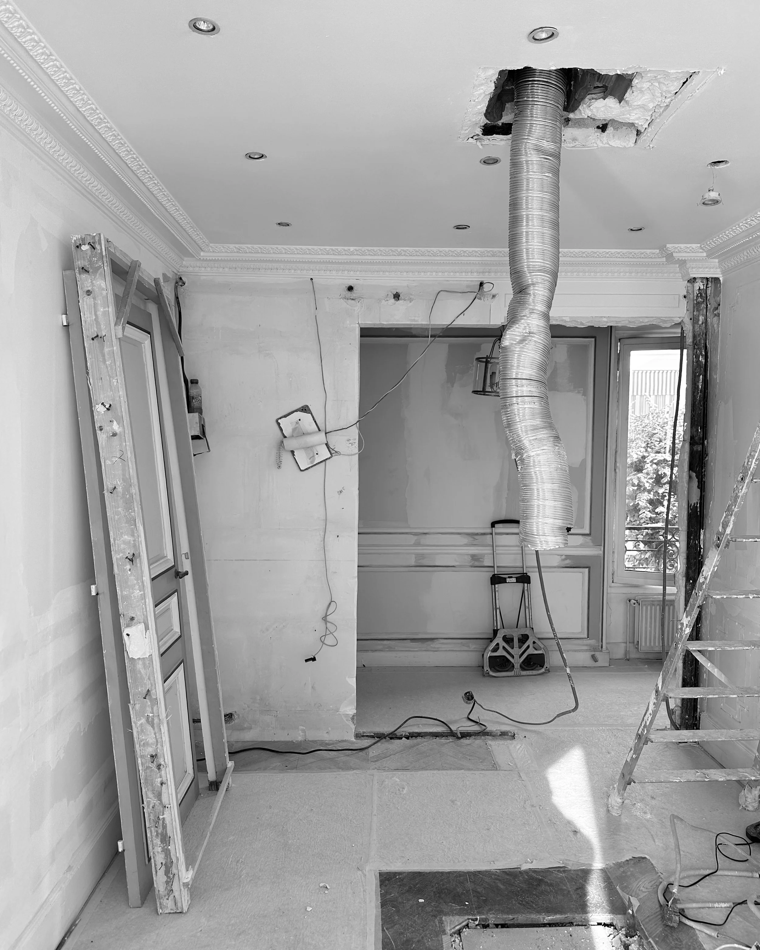 Chambre en rénovation avec un plafond suspendu, un conduit flexible suspendu au plafond, une échelle, une porte et une fenêtre dans la pièce, ainsi que des câbles électriques et des outils.