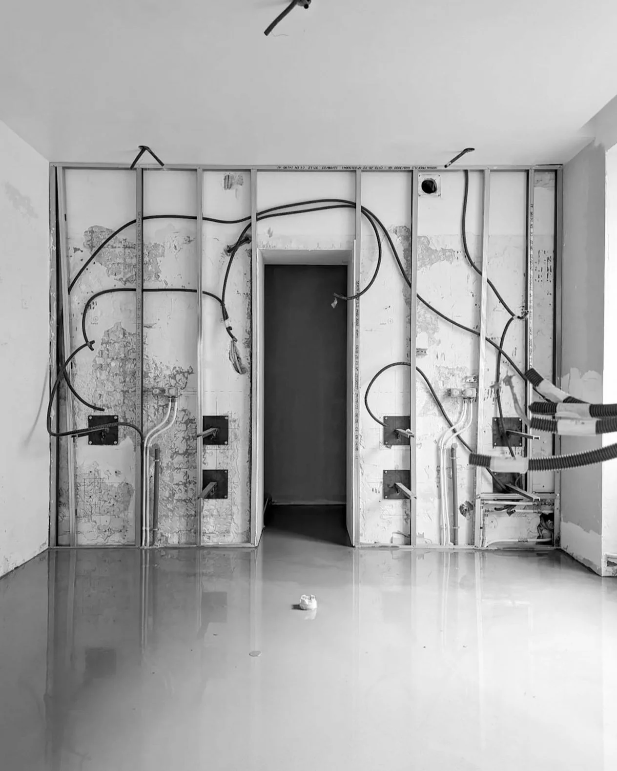 Mur en construction avec câbles électriques et cadres métalliques, pièce en travaux.