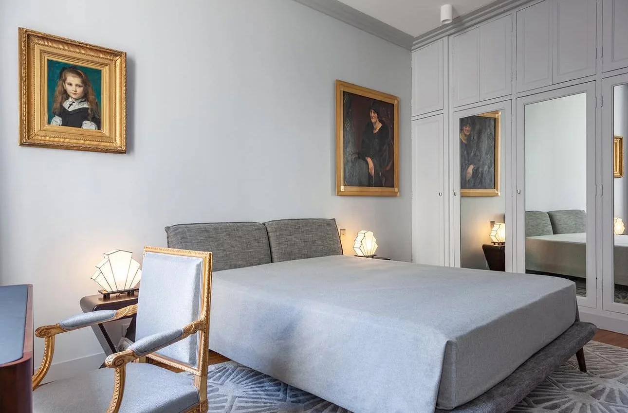 Chambre moderne avec un lit king-size, un mur avec des armoires miroir, des lampes en forme de géodes et des peintures encadrées au mur.