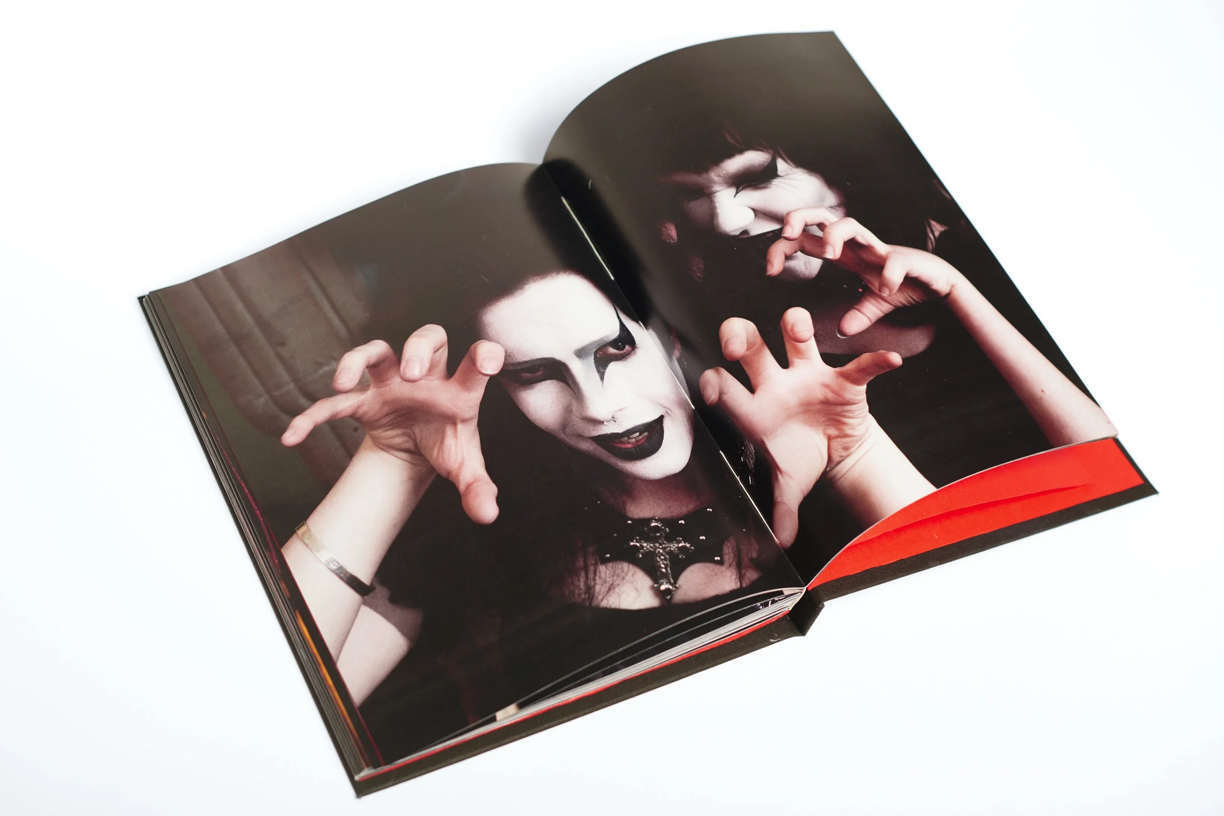 Open magazine featuring two women with goth makeup and dark hair, making playful hand gestures.