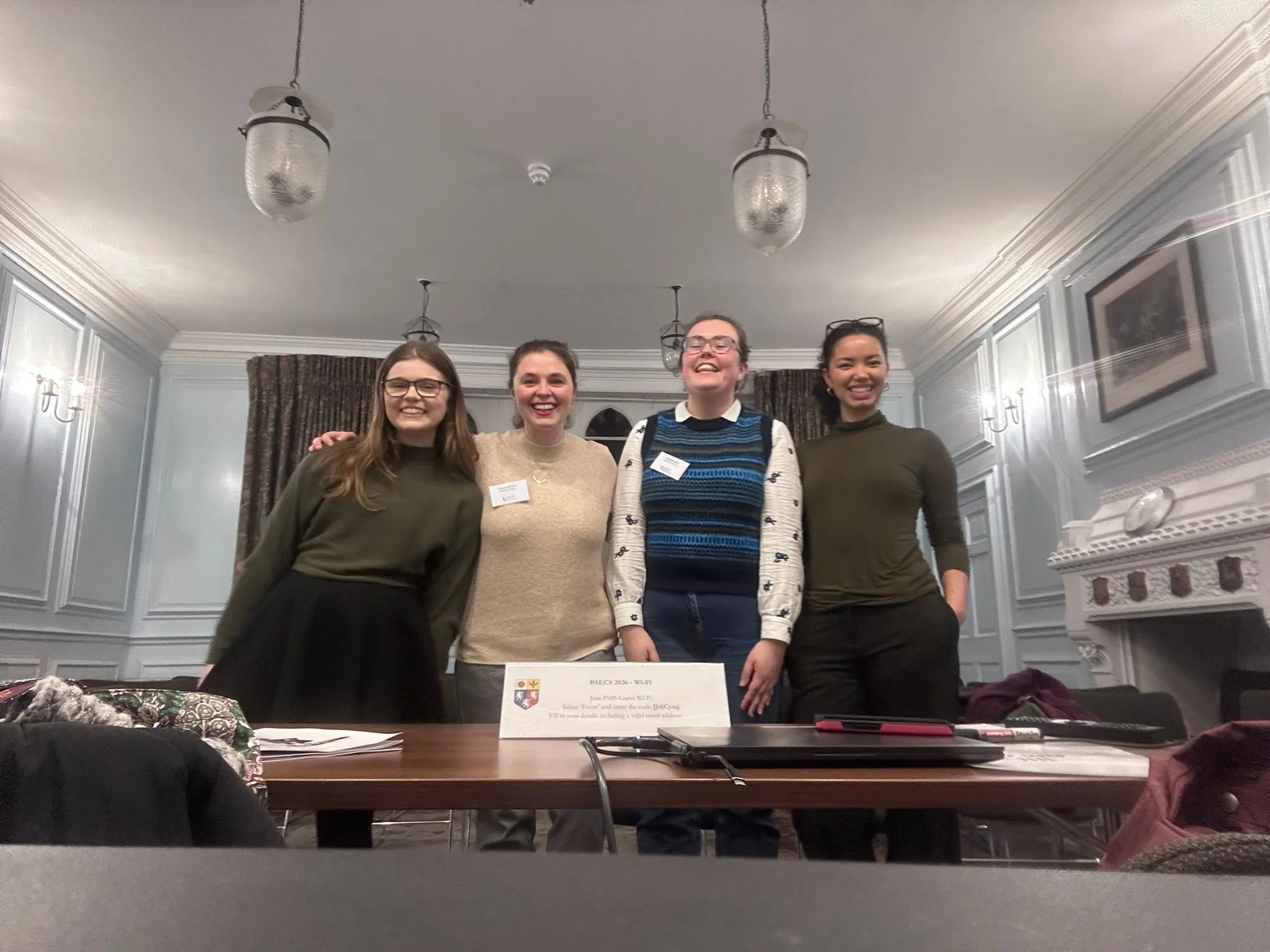Four women standing side by side behind a desk.