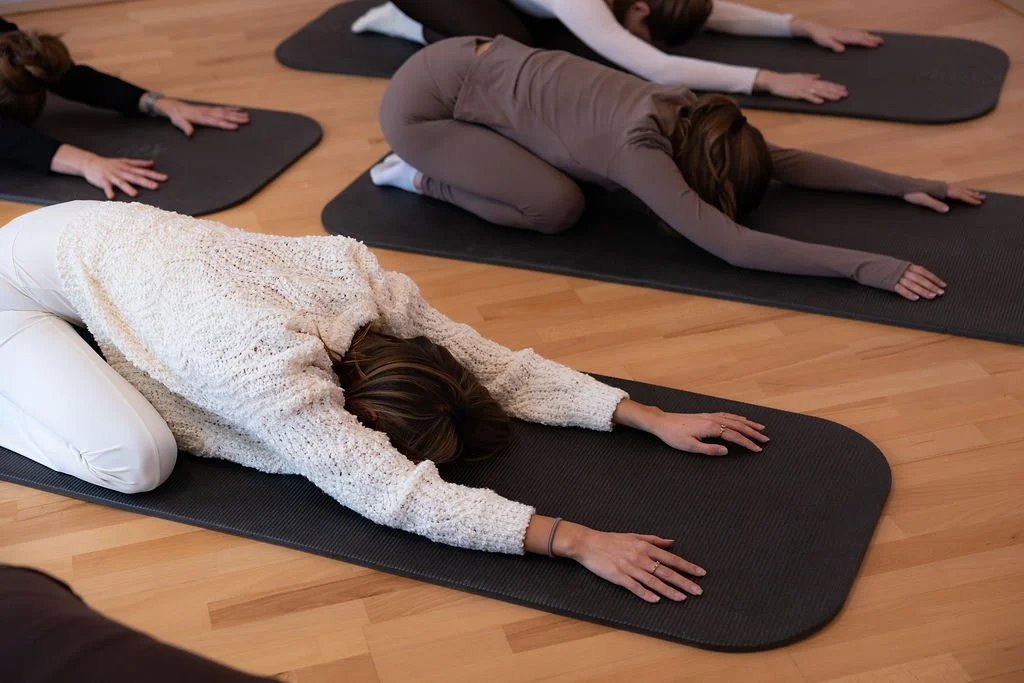 Menschen in einer Yoga- oder Meditationsklasse in der Kindhaltung auf Yogamatten