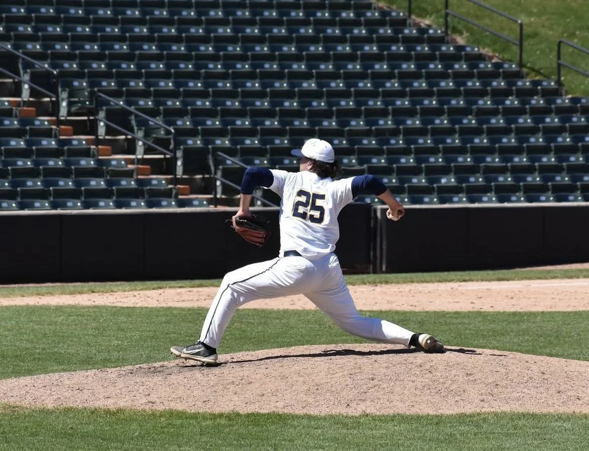 A baseball pitcher in uniform with the number 25 on it is in the process of pitching a ball on the mound at a baseball stadium.
