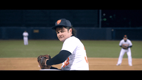 A baseball player in a white and black uniform on a baseball field, with other players in the background.