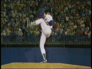 A baseball pitcher in a white uniform throwing a baseball during a game on the field.