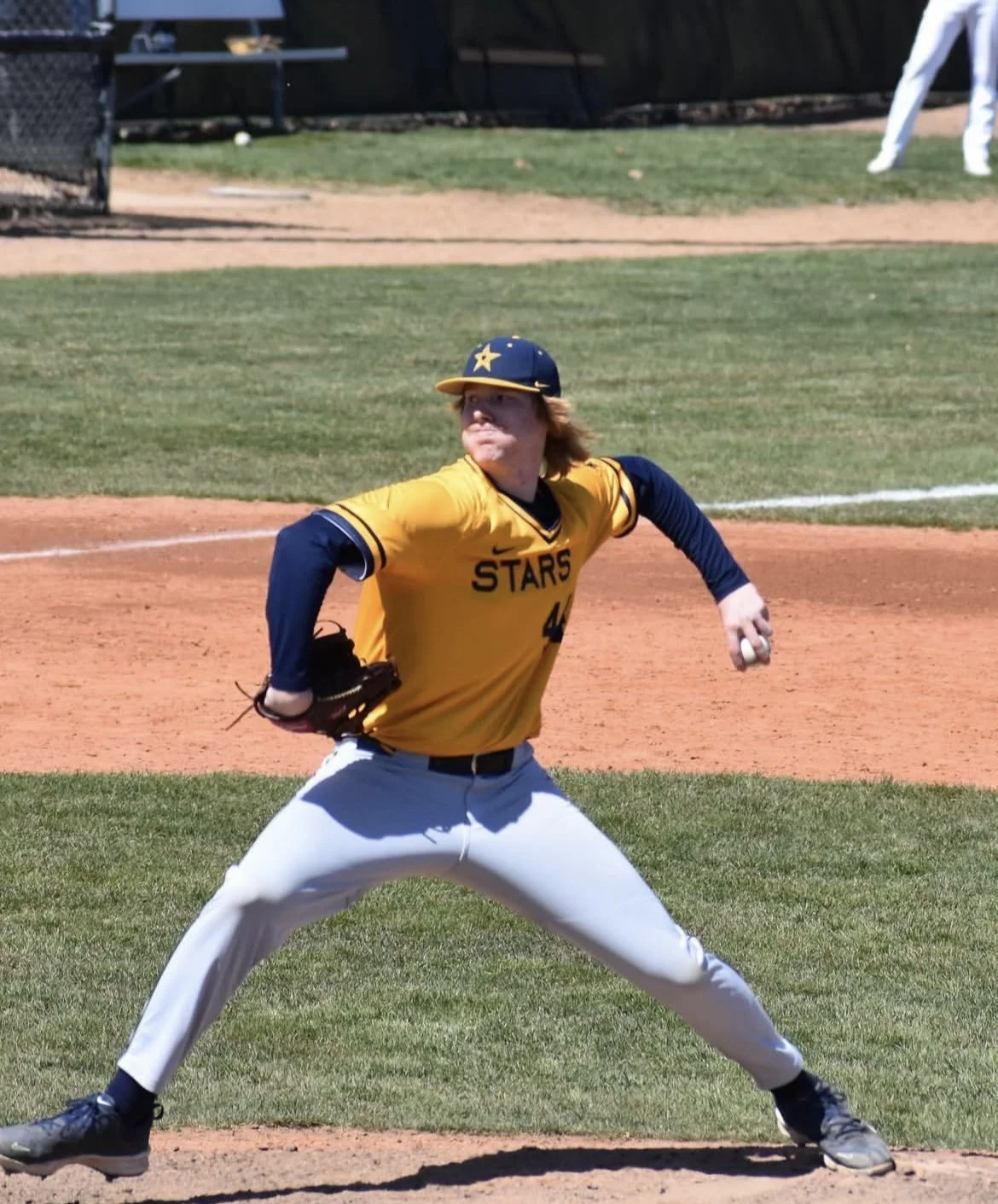 Baseball player in a yellow and blue uniform with a star on the helmet, preparing to catch a ball on a baseball field.