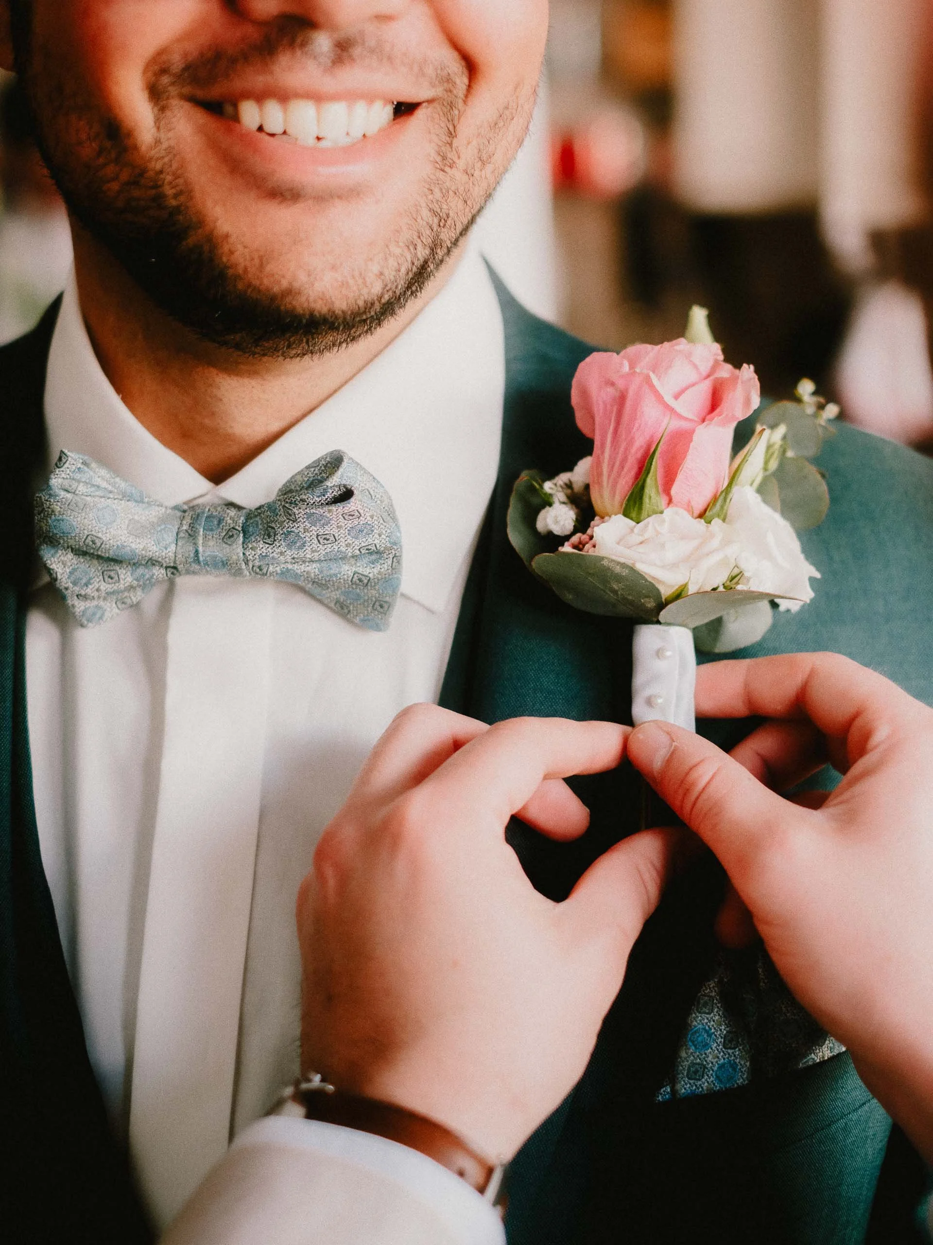 Bräutigam bekommt Ansteckstrauß von Trauzeuge angehängt