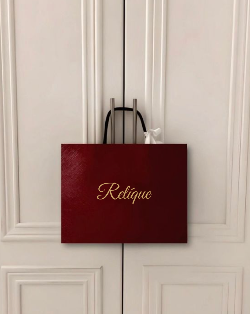 Wit kastdeuren met een rode shoppingtas hangend aan de deurhendel, met het woord 'Relique' erop.