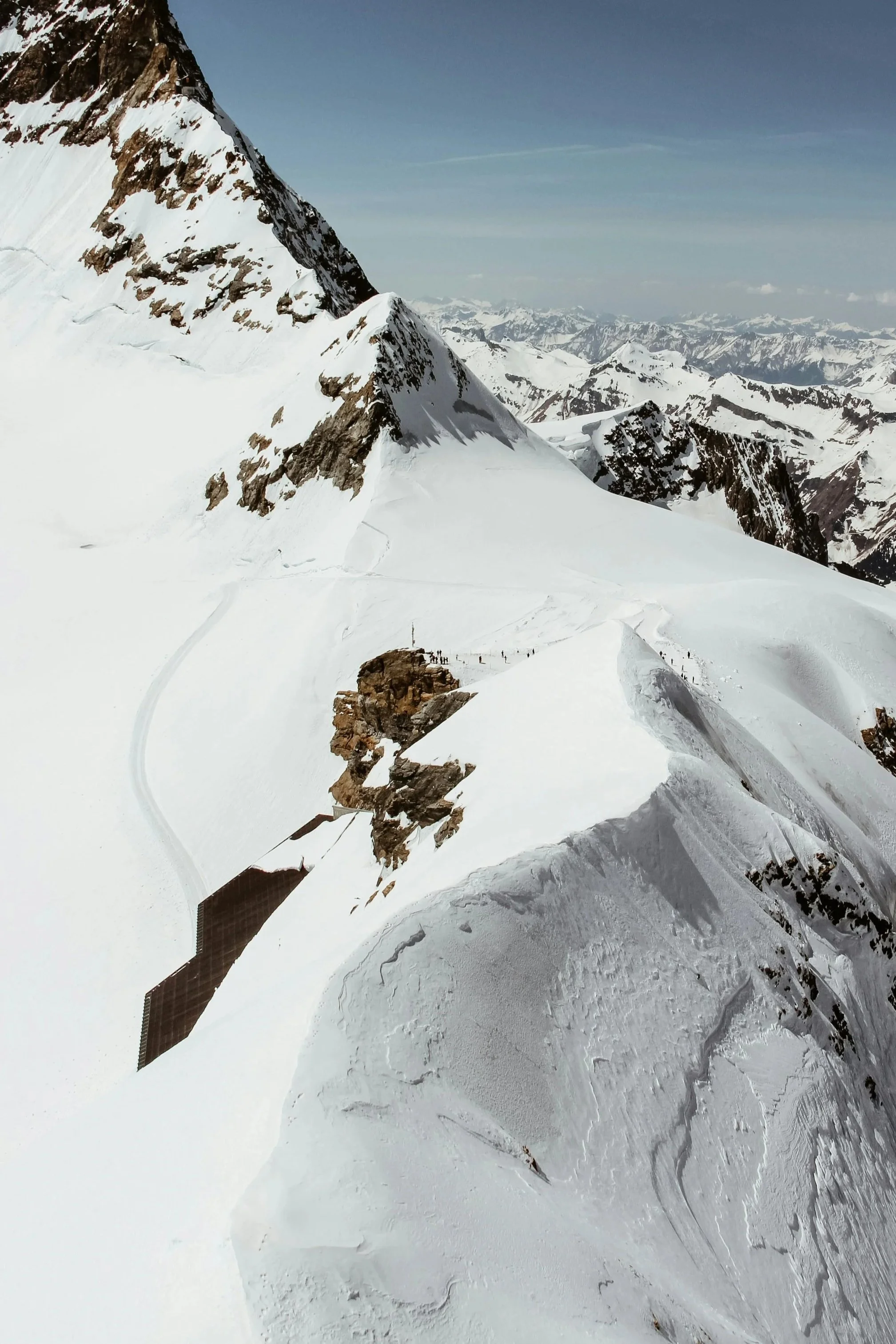 Montagnes enneigées avec un glacier, un sommet rocheux, et un panneau solaire sur la glace.