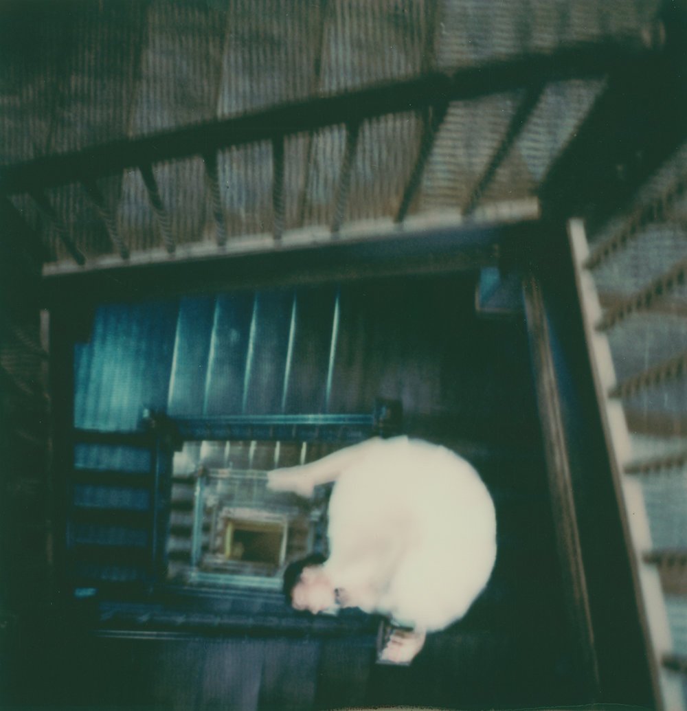 A white cat curled up and sleeping on a staircase in a dimly lit environment.