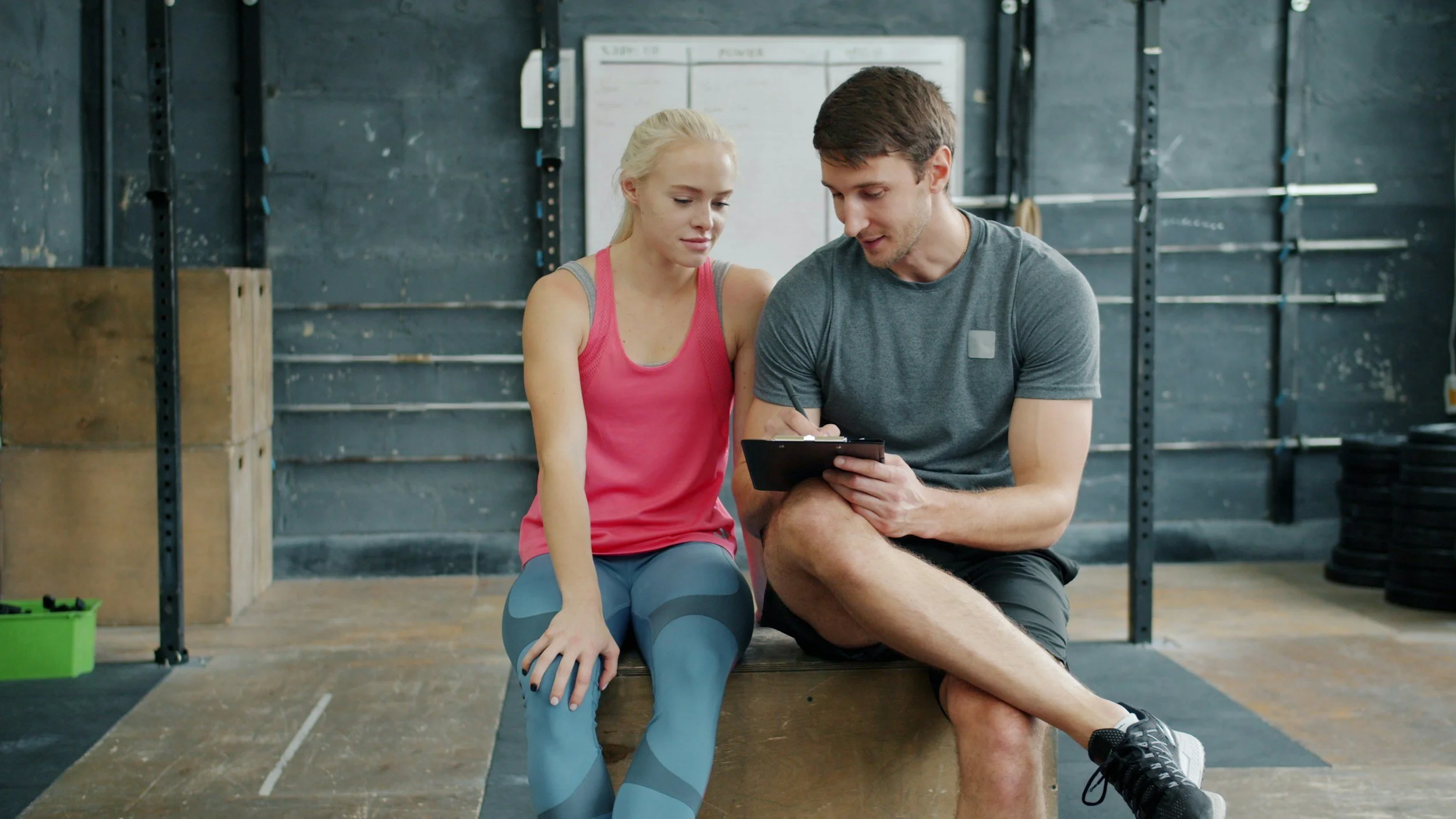 A trainer in gym clothes going over a plan with a client