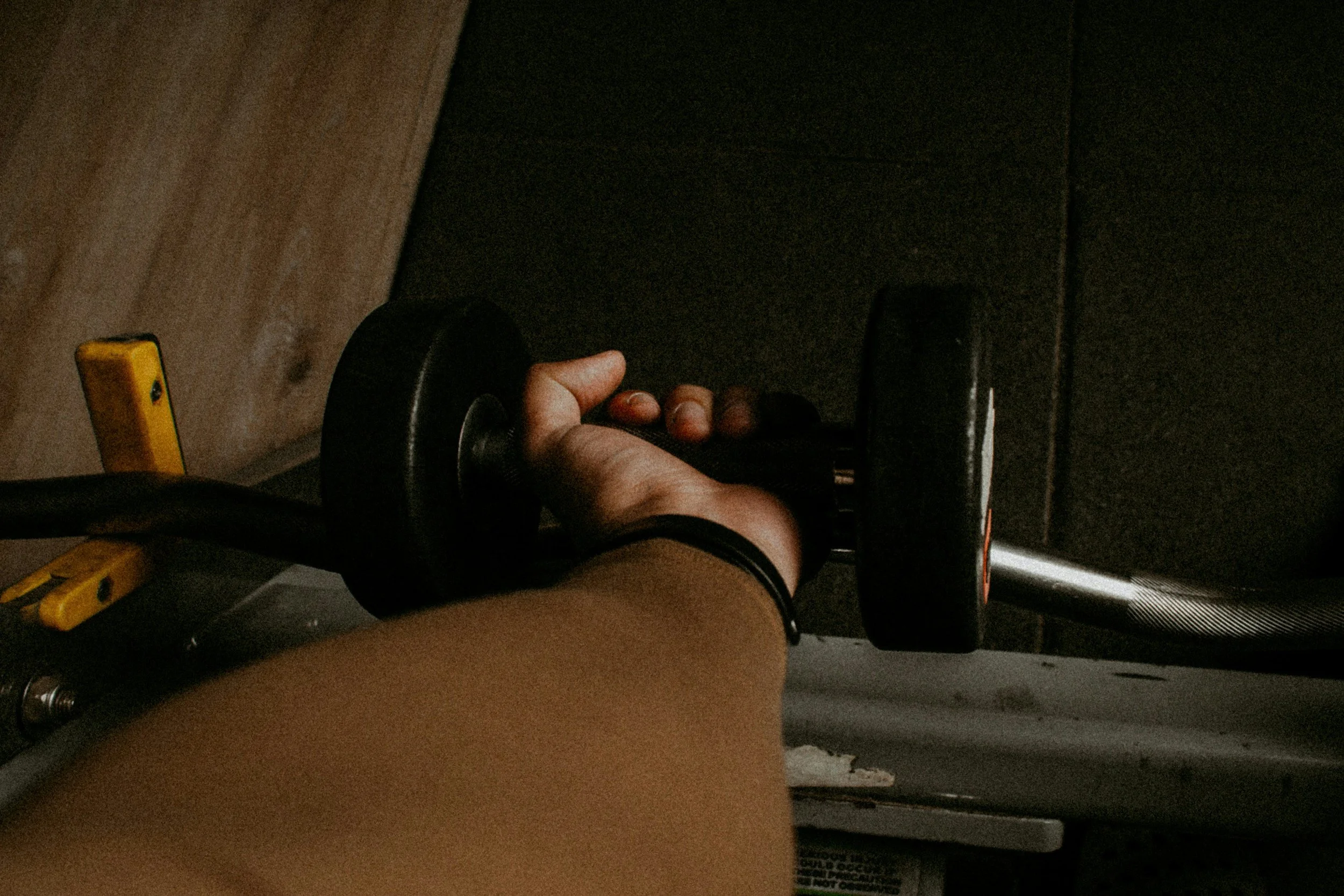 Arm reaching down to pick up a dumbbell