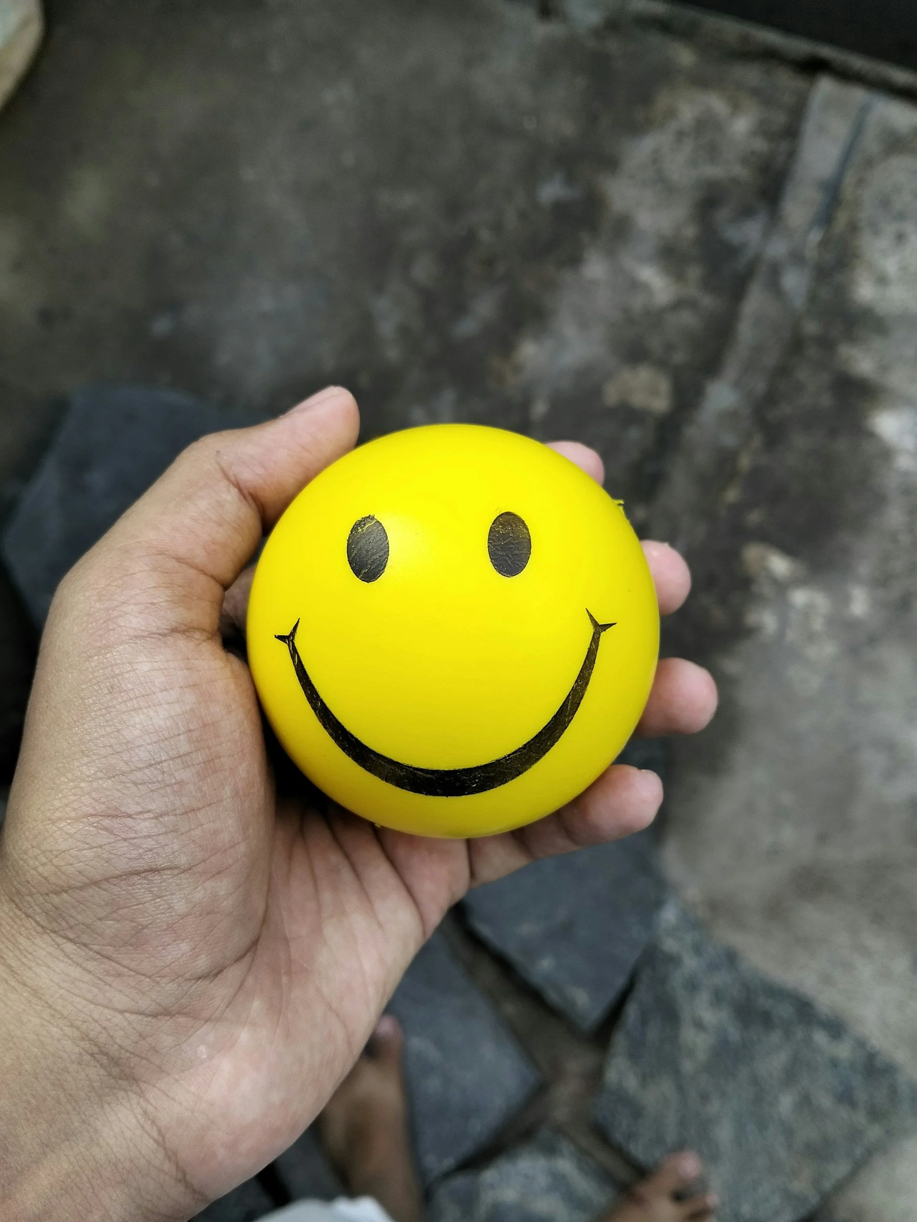 hand holding a smiley face ball