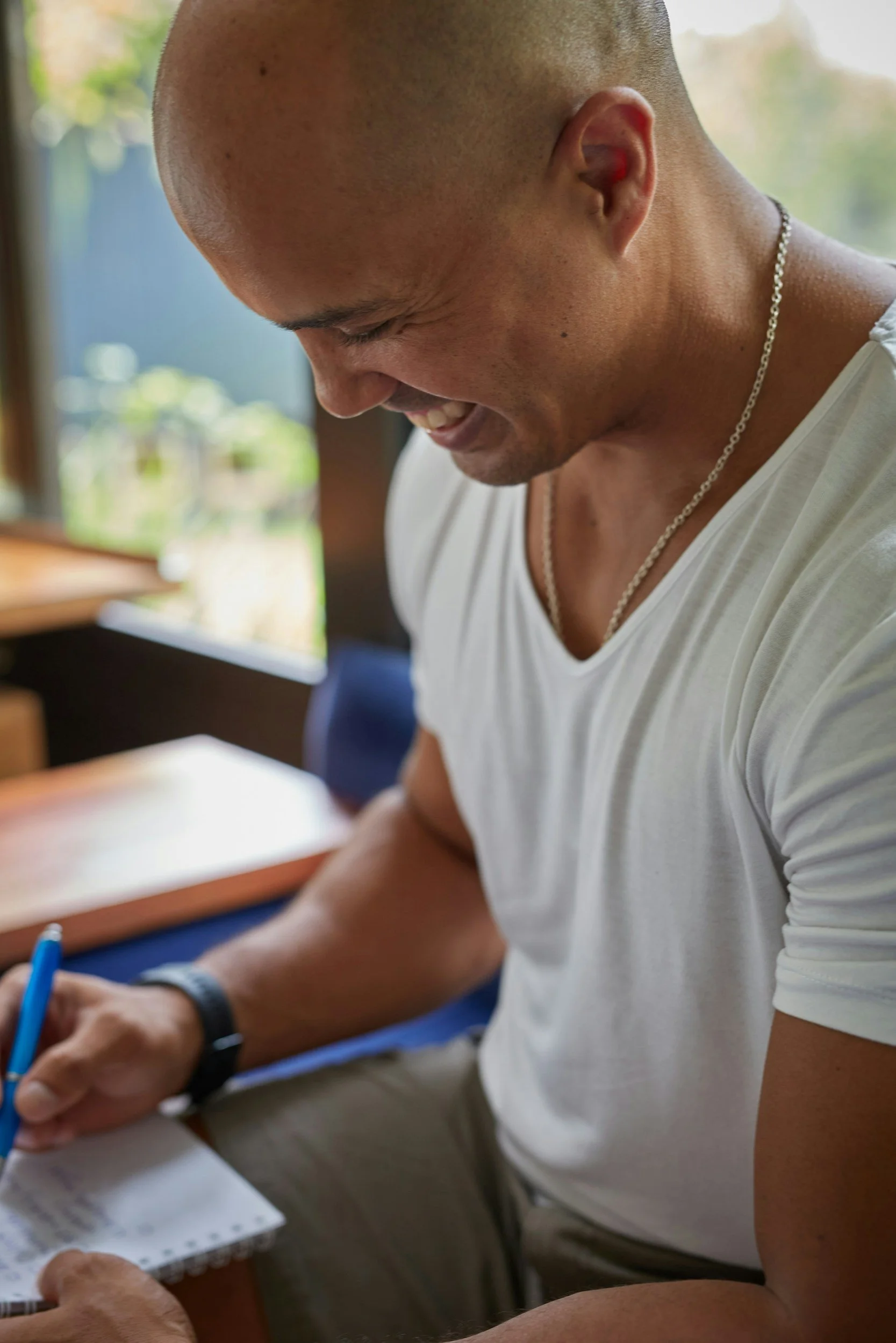 man writing in journal while smiling