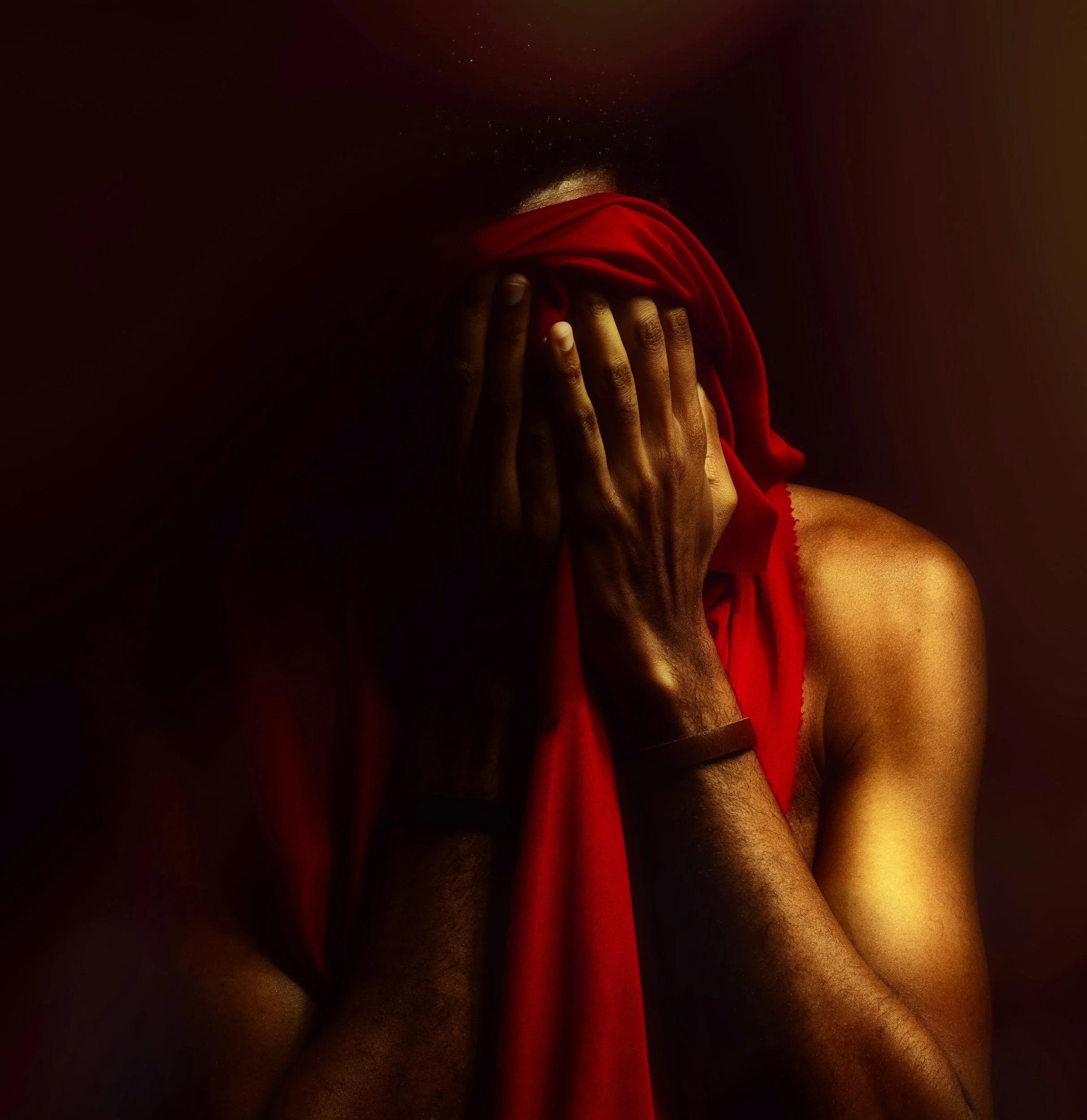 Man covering his face in the dark with a red shirt