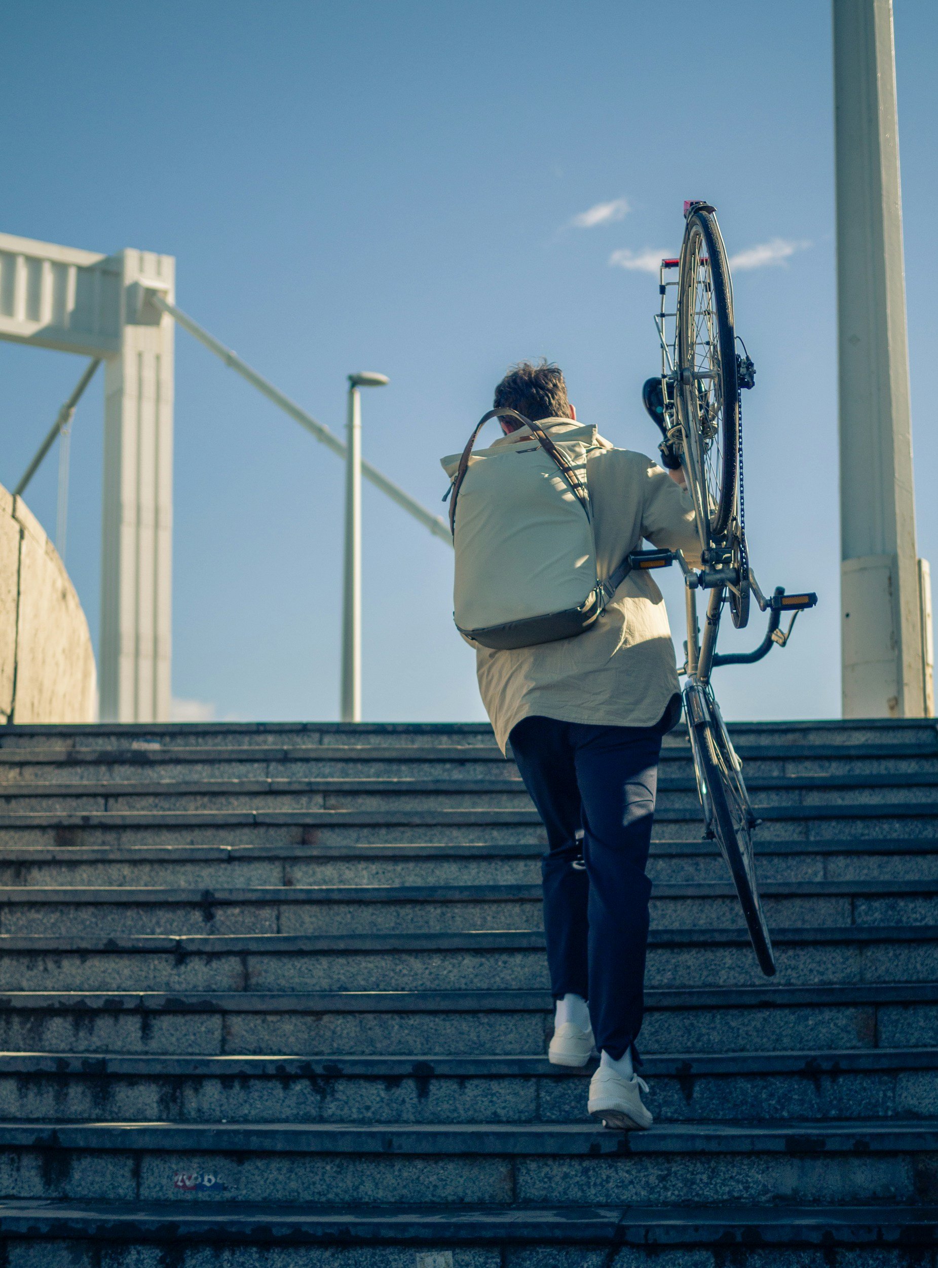 person carrying bicycle up stairs outside