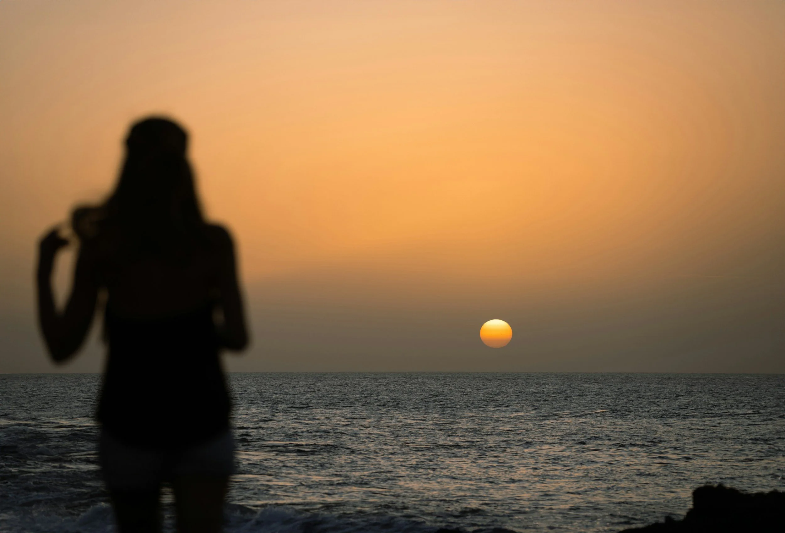 silhouette of person watching sunrise on a beach