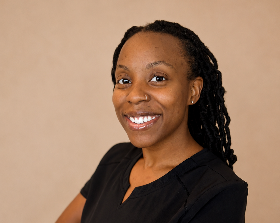 Portrait of a woman with braided hair, smiling, wearing a black top, against a neutral background.