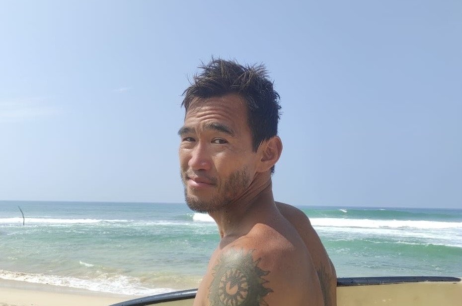 海辺でサーフボードを持つ男性の写真