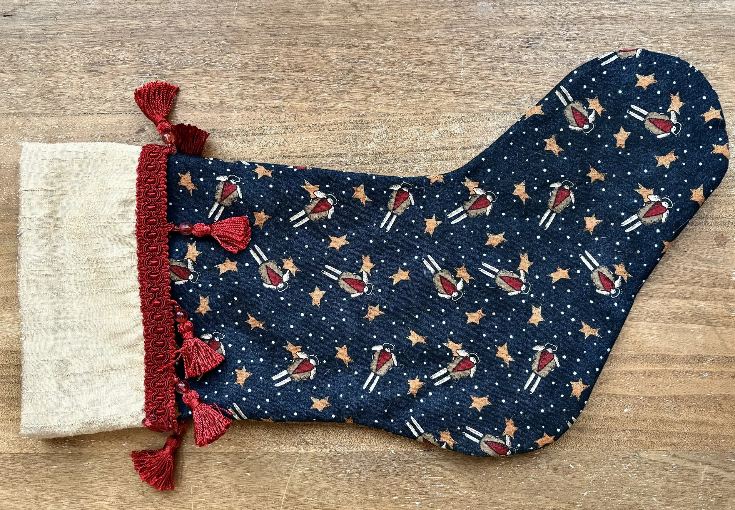 Lined Christmas stocking using a blue cotton print with space men, dots, and stars with a gold silk cuff and red braid made by Marina Bosetti for her husky Stella.