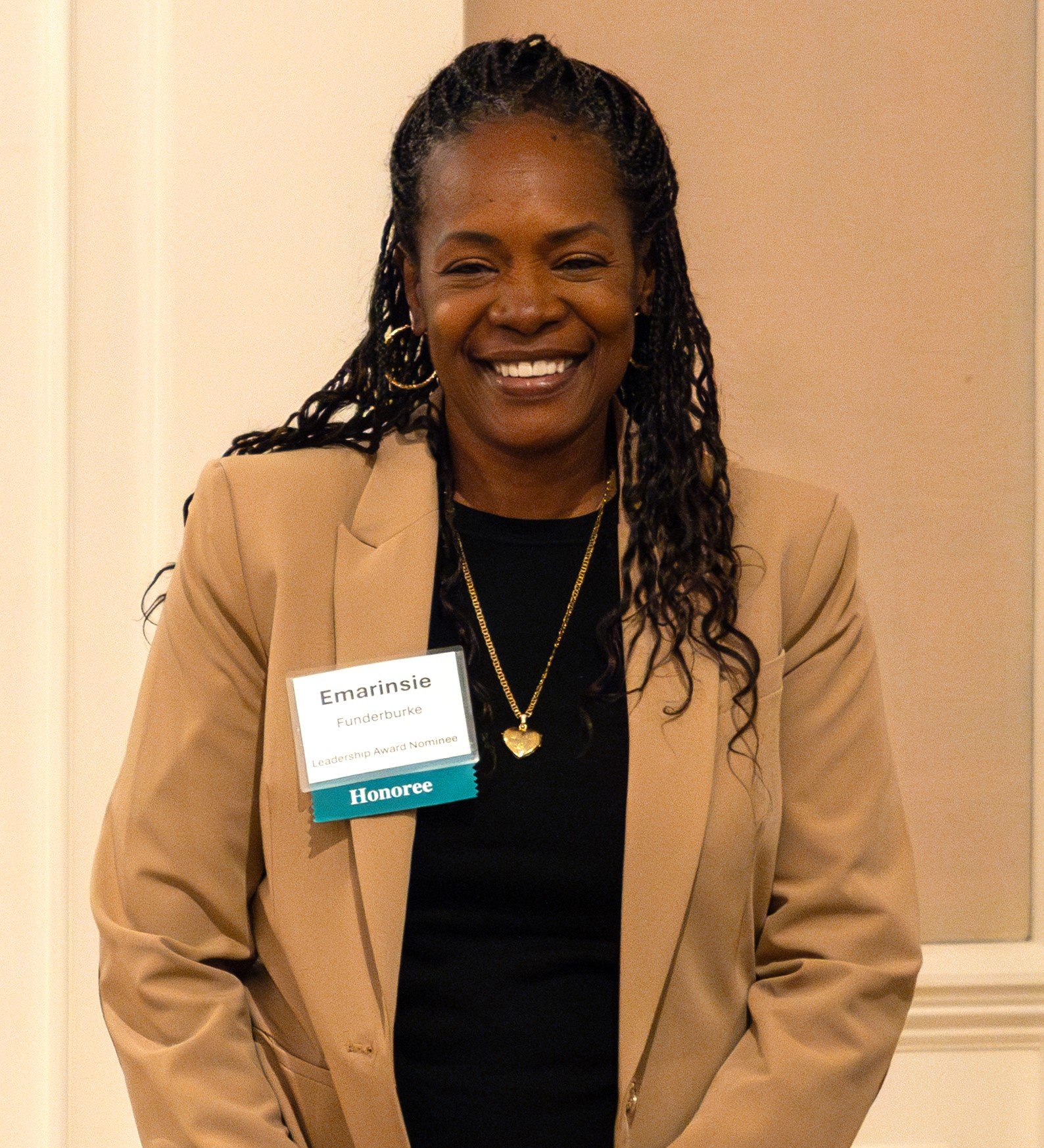 A geothermal area with steam rising from hot springs, surrounded by colorful, eroded rocks and patches of snow on distant mountains under a cloudy sky.