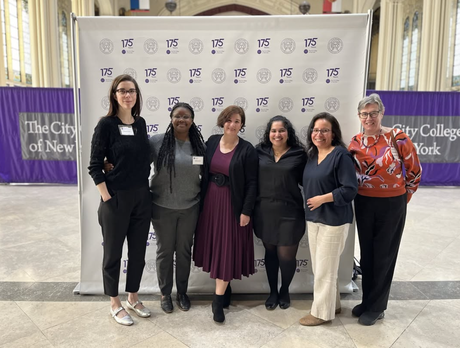 Group of six women standing in front of a backdrop with logos, celebrating the 175th anniversary of The City College of New York.