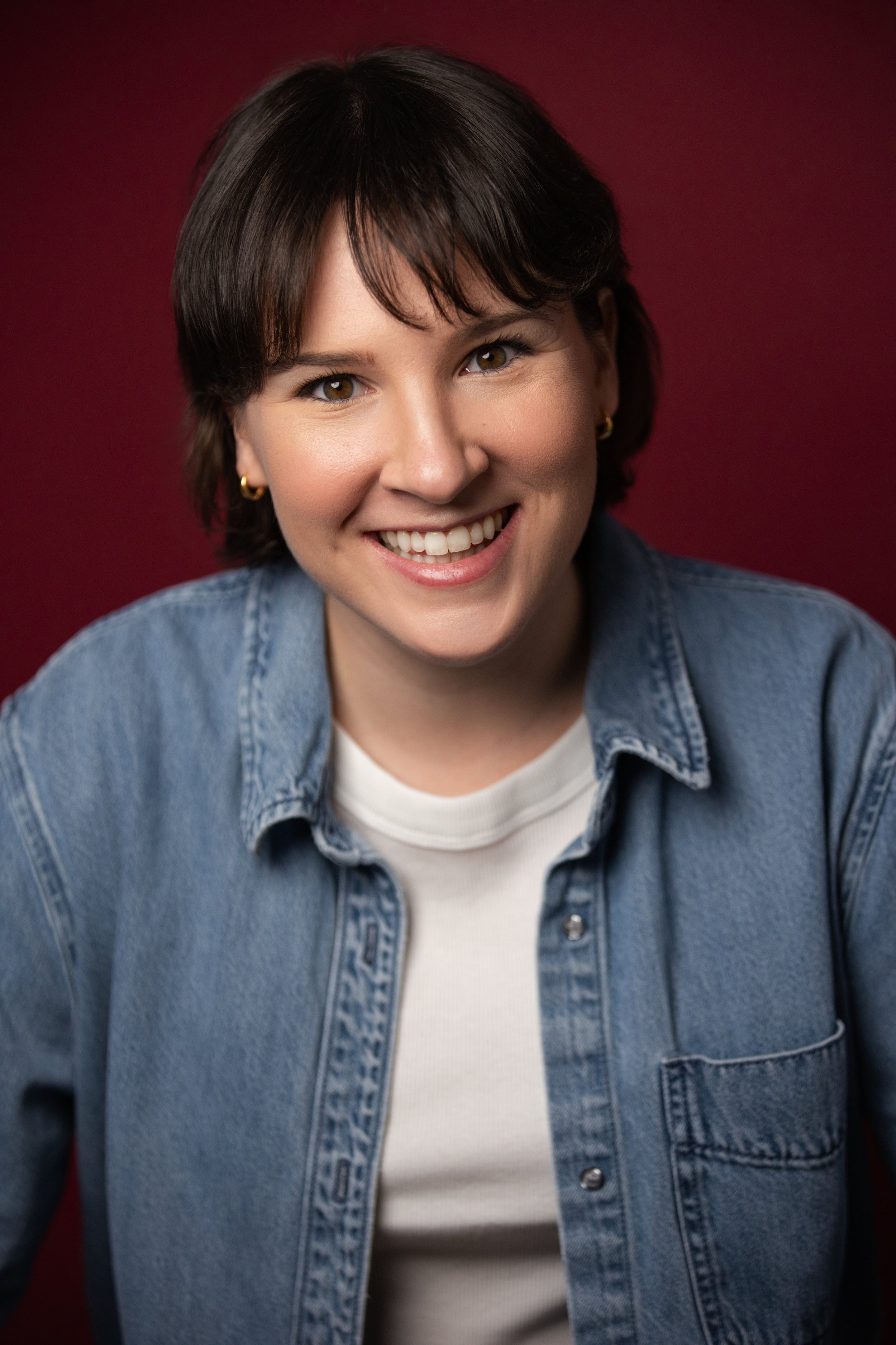 Katie Jacoby's potrait with a smiling face on a burgundy backdrop.