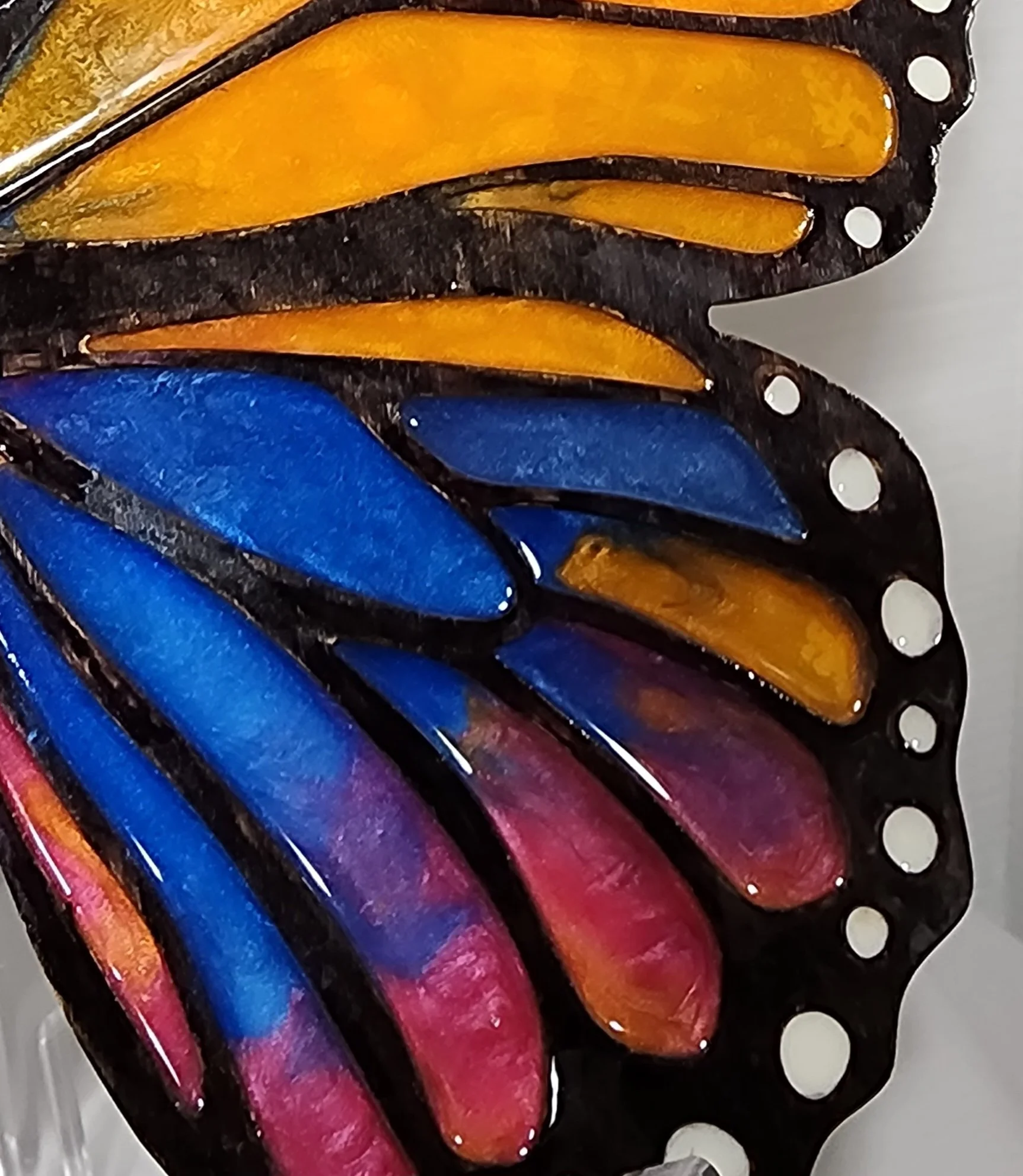 Close-up of a stained glass artwork featuring colorful, curved glass pieces in orange, blue, purple, and pink, outlined by black metal.