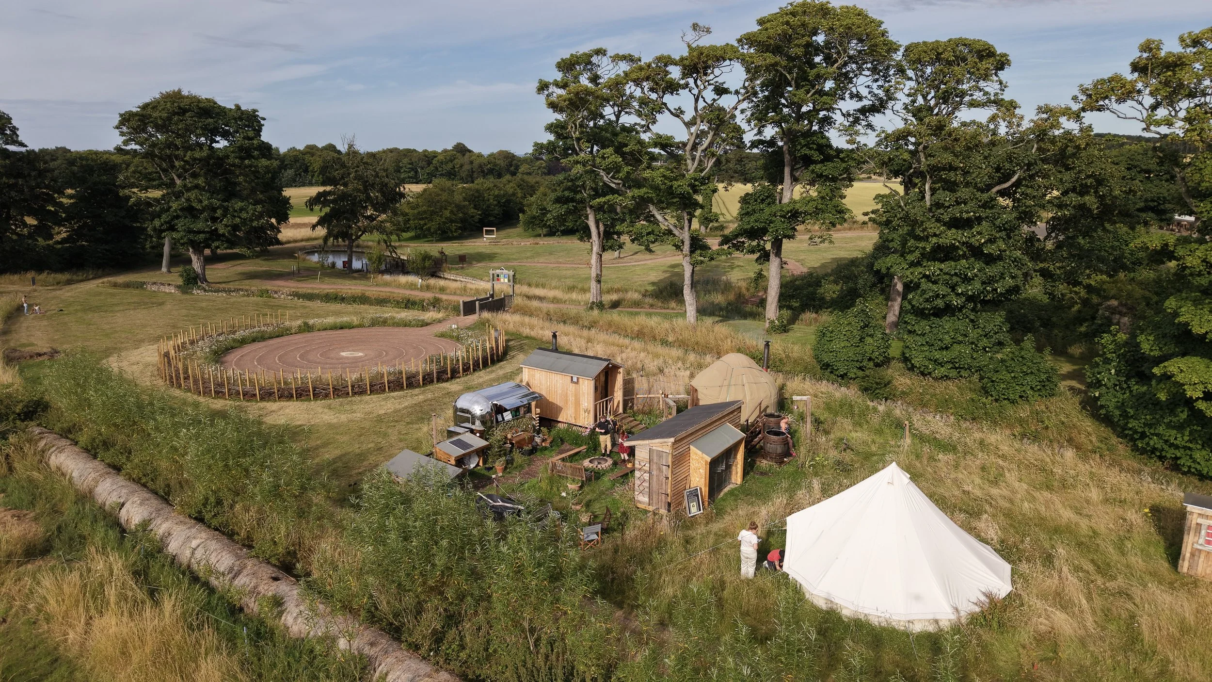 Hot & Bothy Sauna from above, drone view of the beautiful countryside surrounding the sauna, and the labrynth next door. Huge old trees and wild fields.
